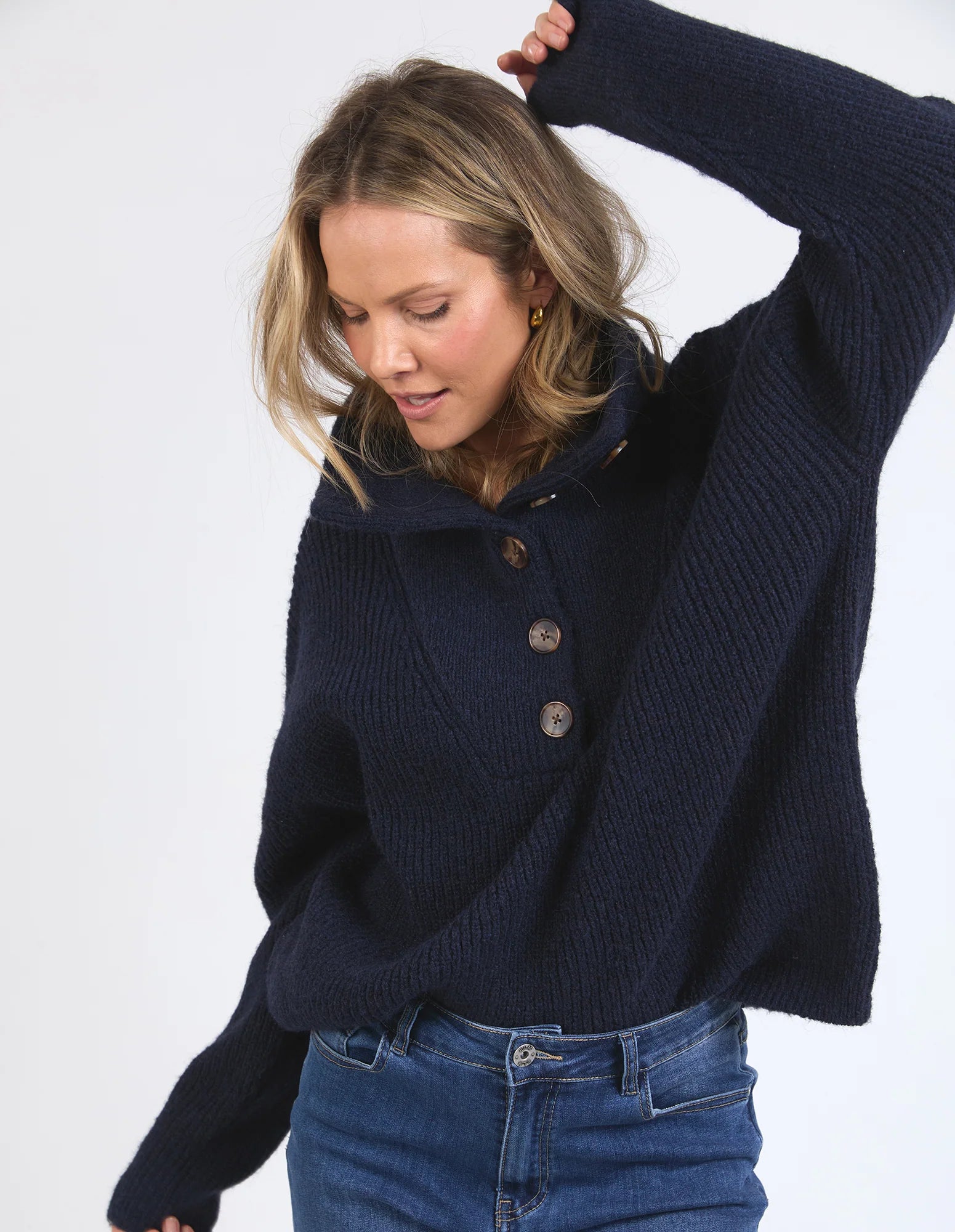 Image of Woman wearing a Elm navy blue sweater with brown buttons on a white background