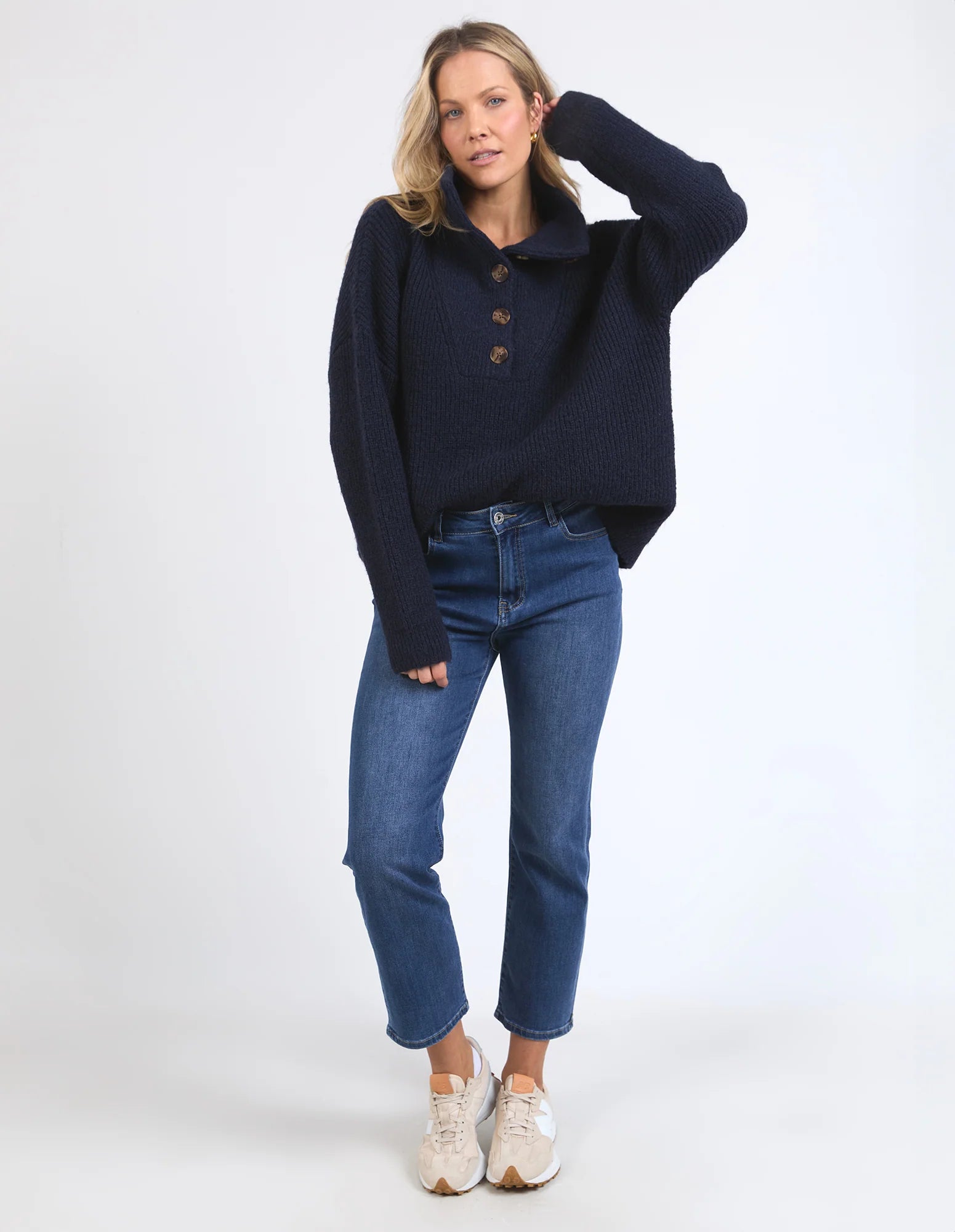 Image of Woman wearing a Elm navy sweater and blue jeans on a white background