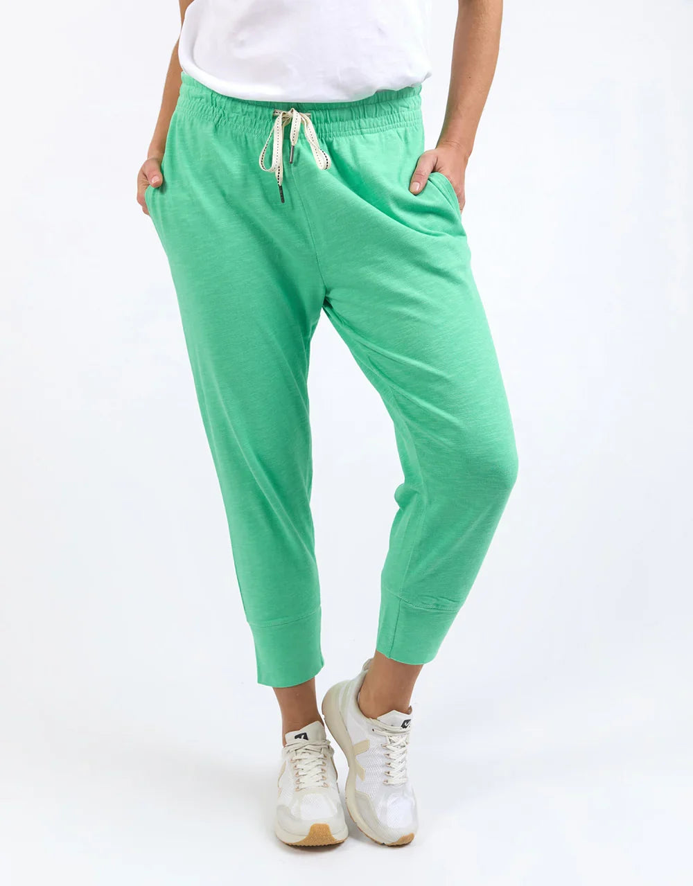 Image of A woman wearing Elm bright mint green jogger-style pants with a white drawstring waist, shown from the torso down against a plain white studio background.
