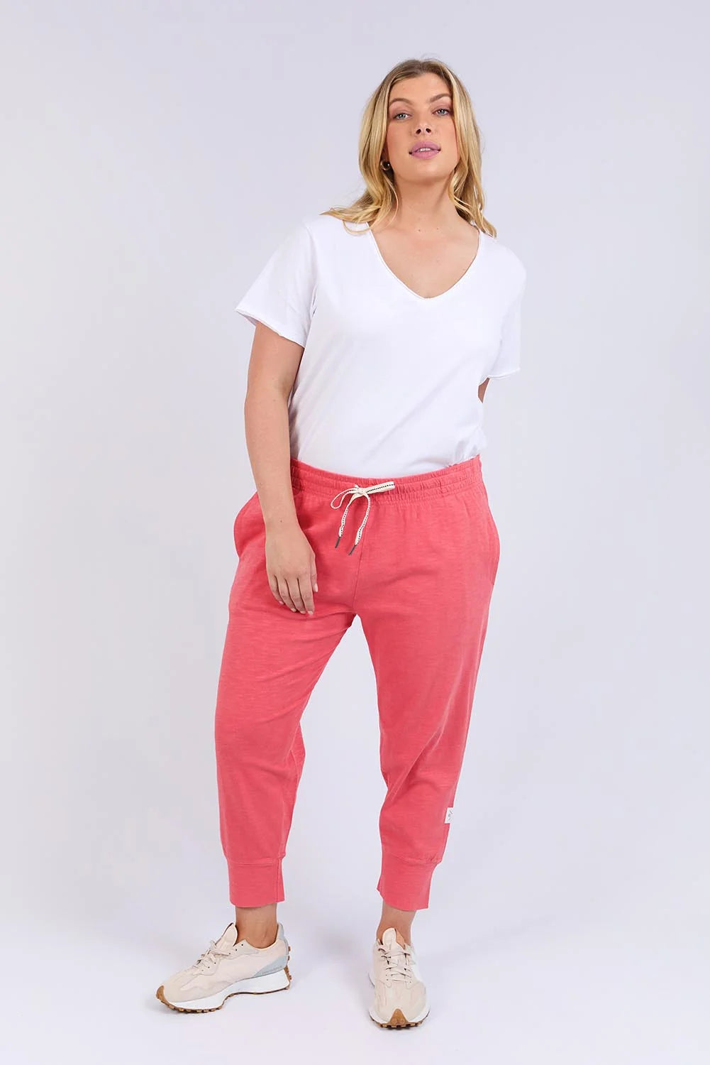 Woman wearing a white t-shirt and Elm pink jogger pants on a white background