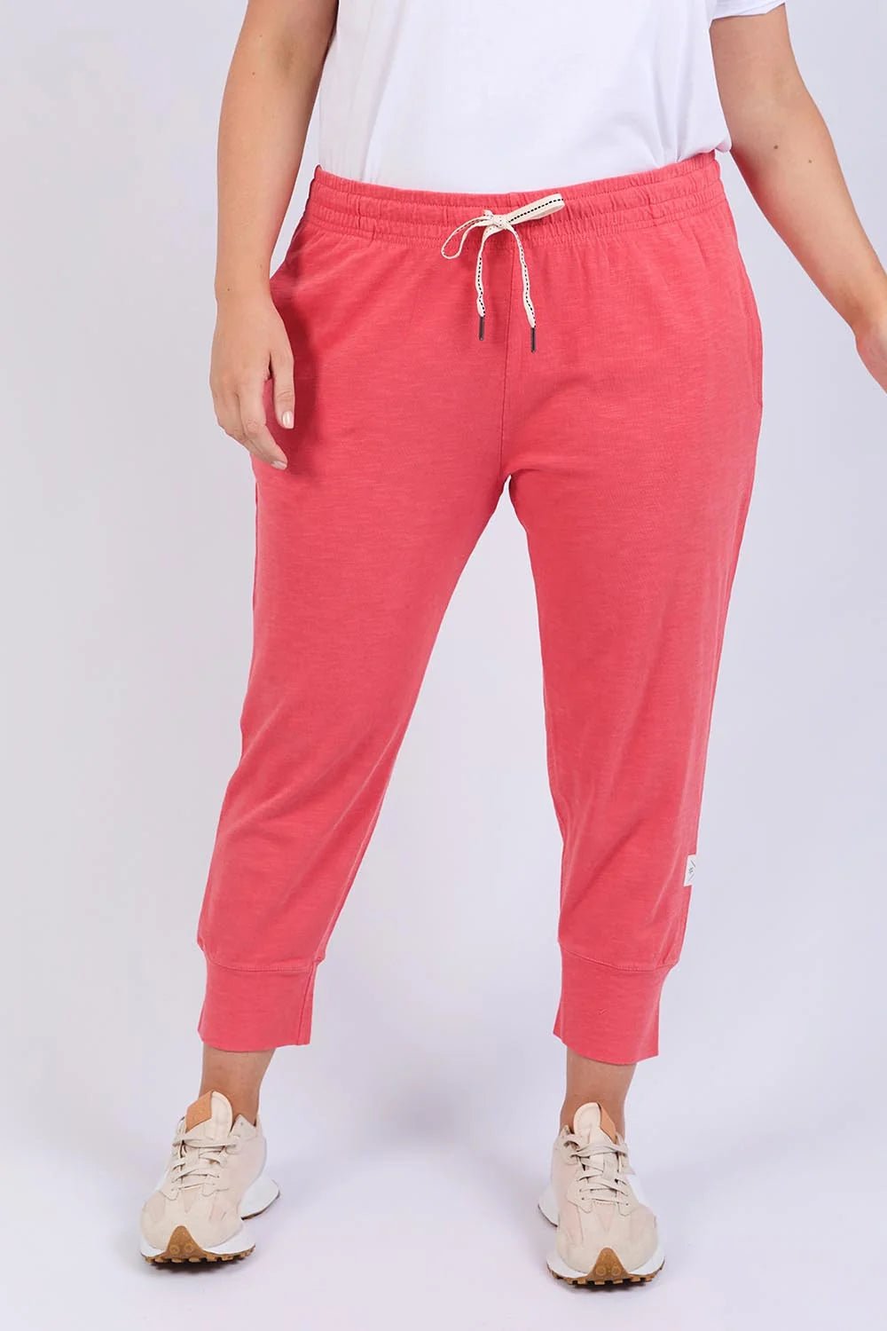 Woman wearing Elm pink jogger pants with a white background