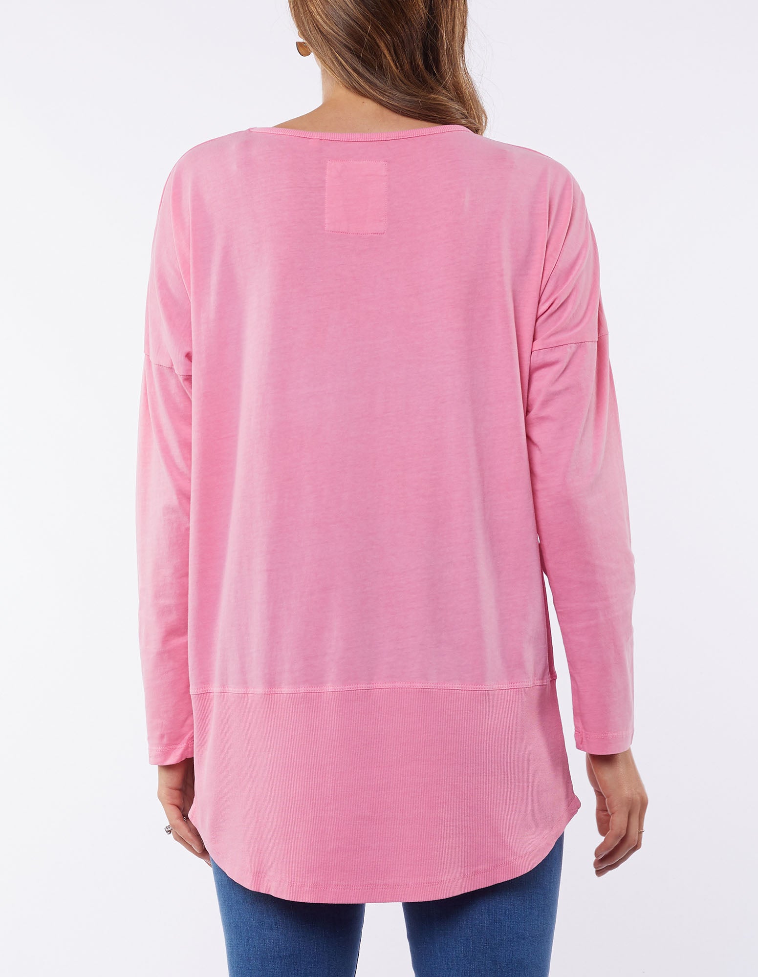 Image of A woman wearing a Elm long-sleeved bubblegum pink t-shirt with a scoop hemline.