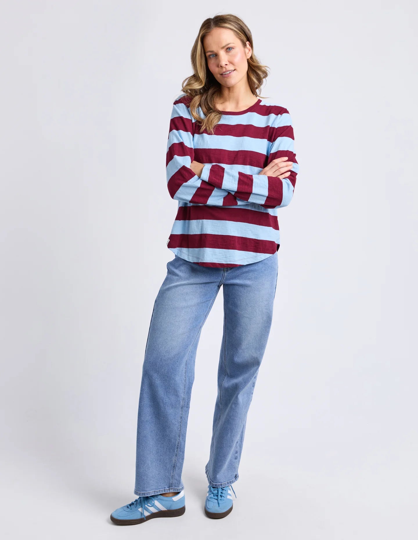 Woman wearing a Elm striped sweater and jeans on a white background
