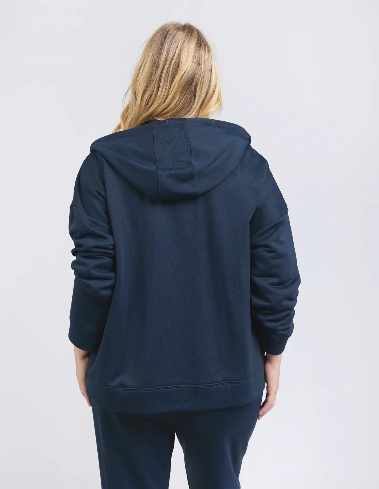 Image of Woman wearing a Elm navy blue hoodie and pants on a light gray background