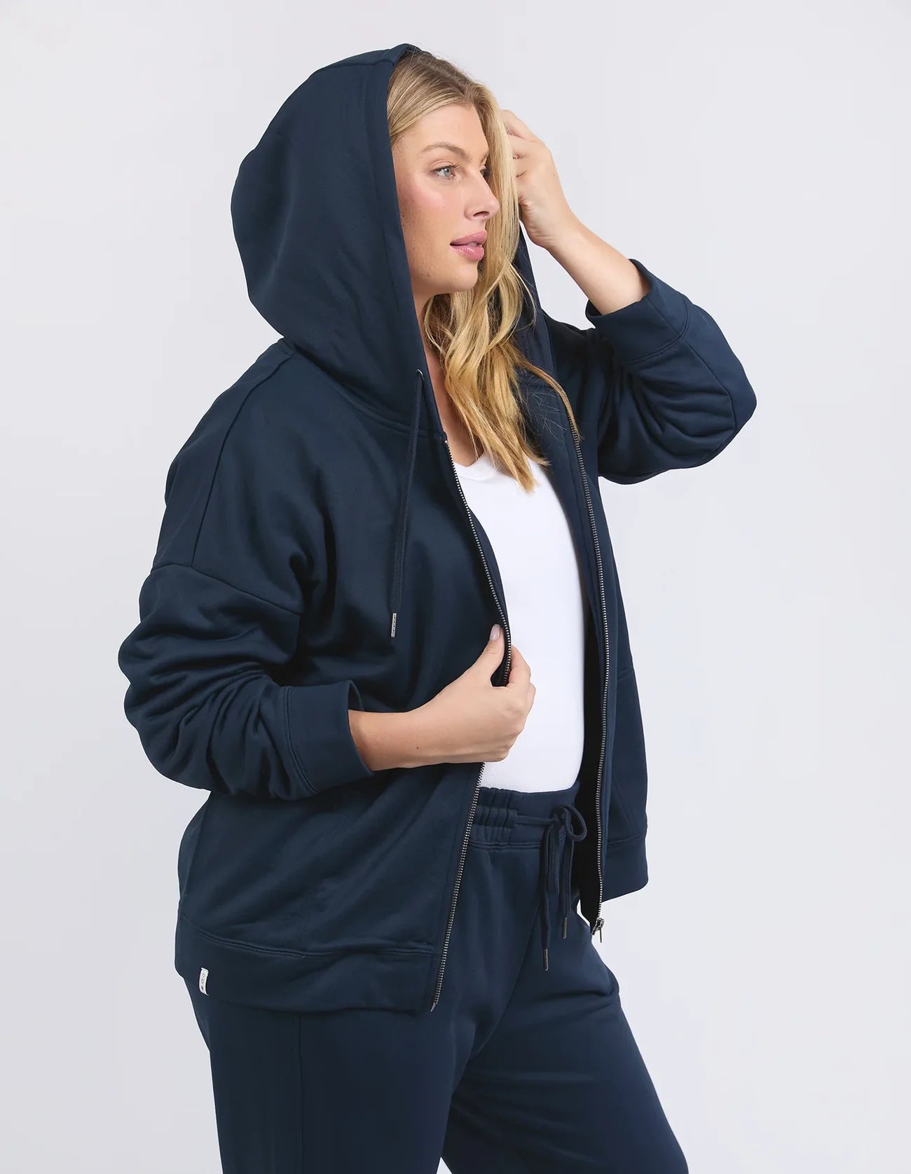 Image of Woman wearing a Elm navy blue tracksuit against a white background