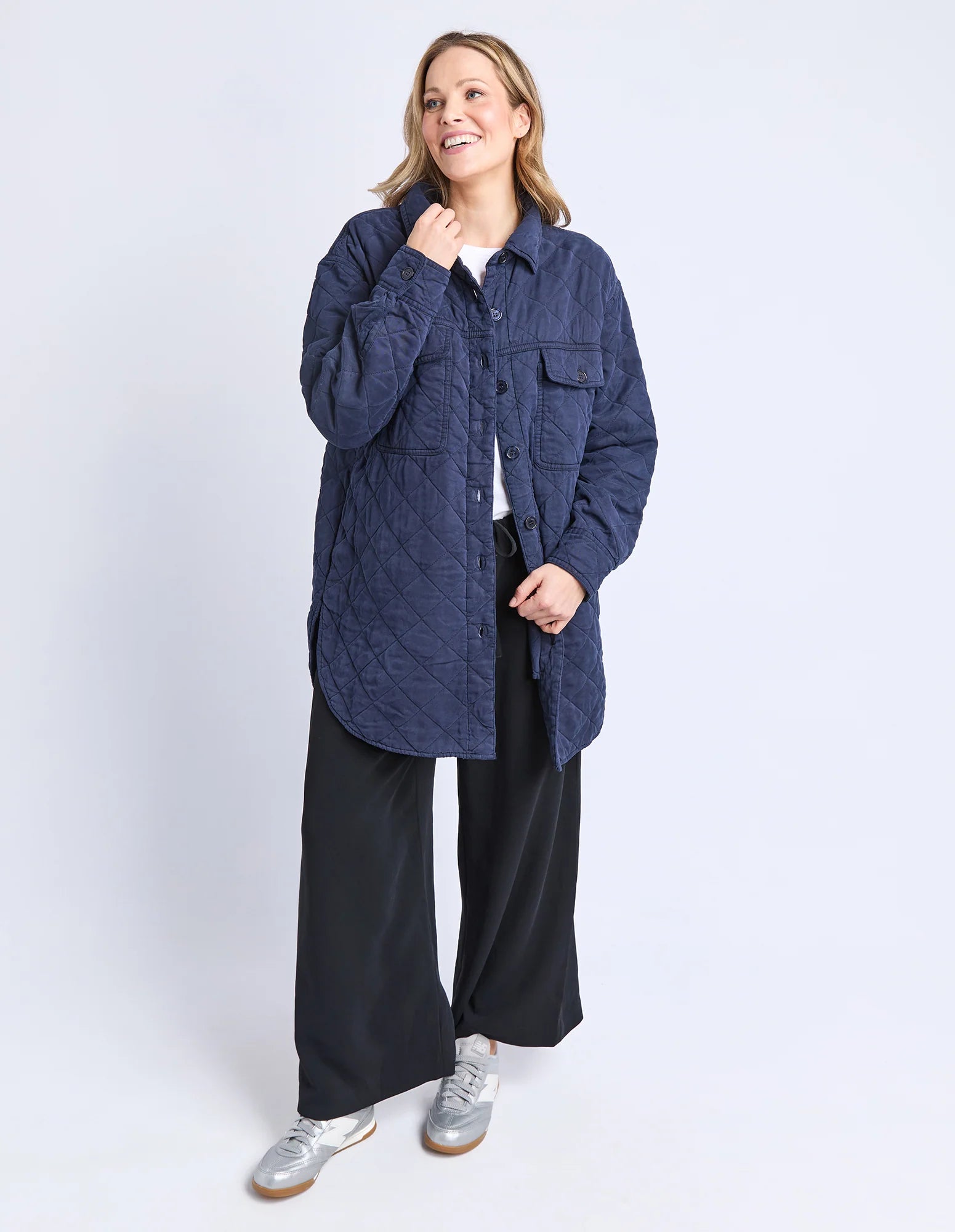 Image of Woman wearing a Elm blue quilted jacket and black pants on a white background