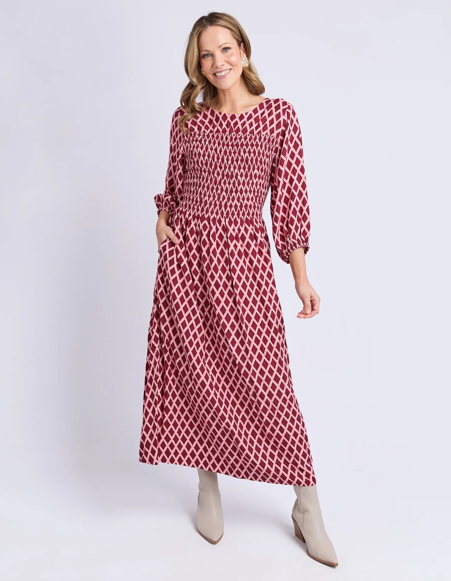 Woman wearing a Elm red and white patterned dress on a white background
