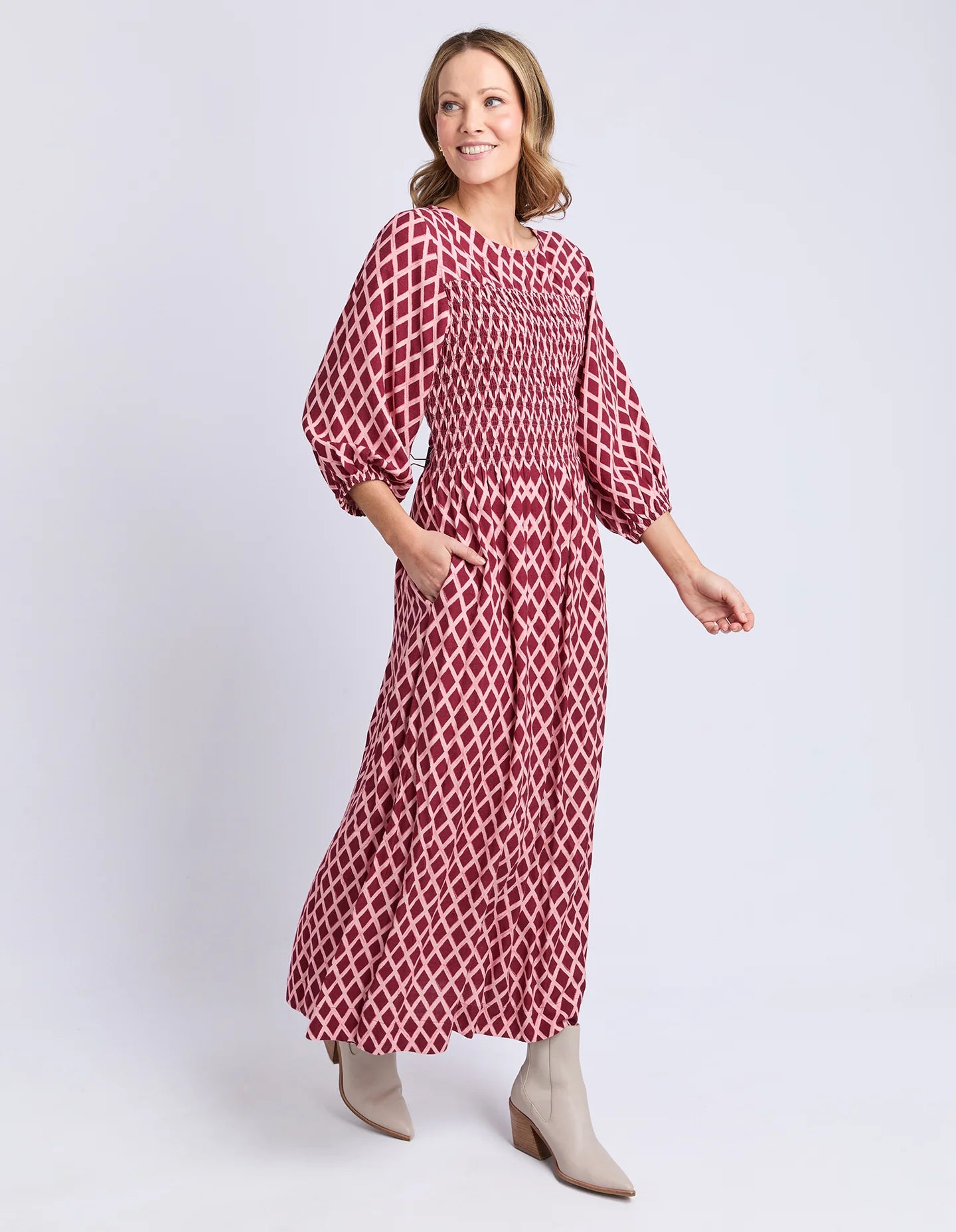 Image of Woman wearing a Elm red and white patterned dress on a light gray background