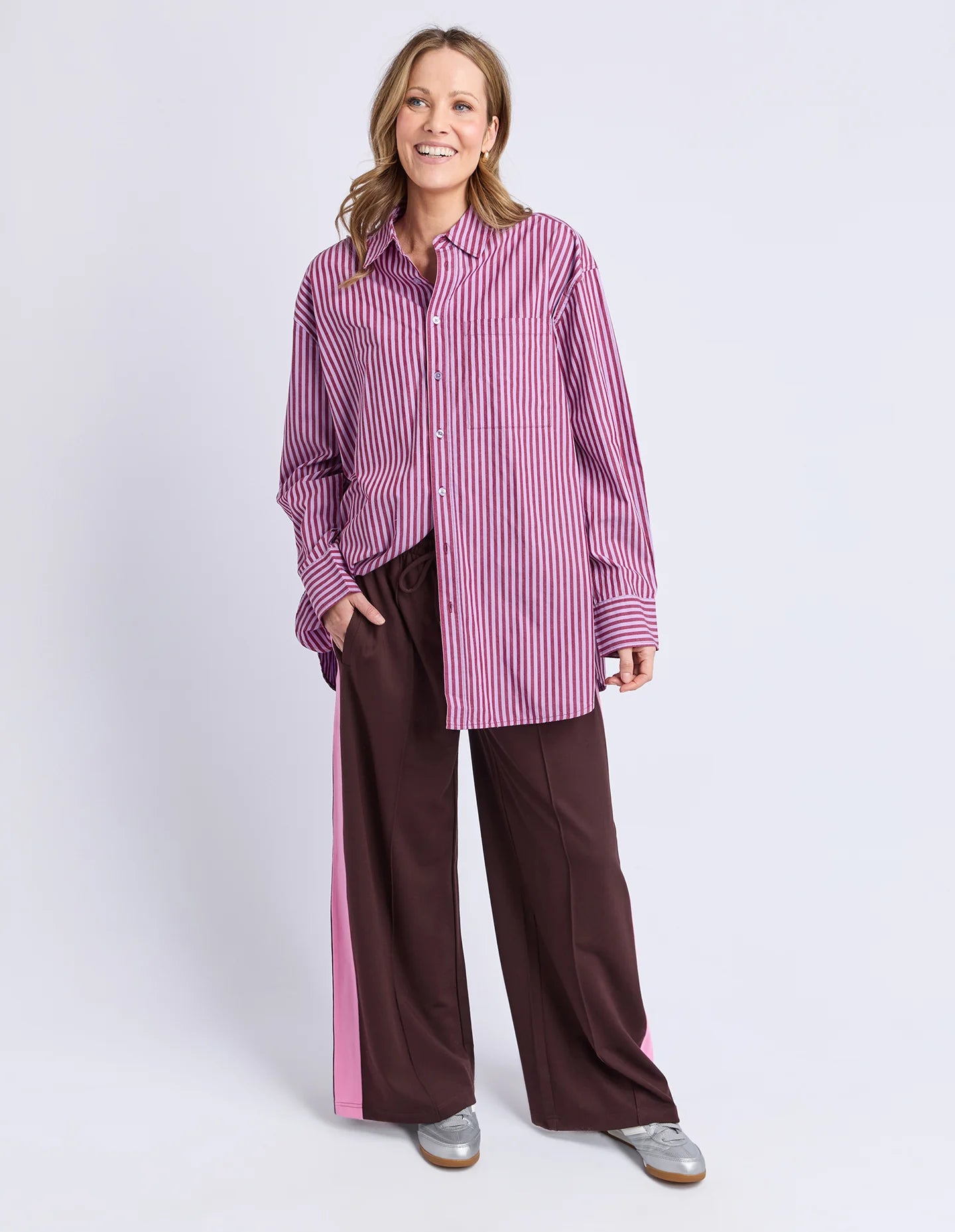 Image of Woman wearing a Elm pink and white striped shirt with brown pants on a white background