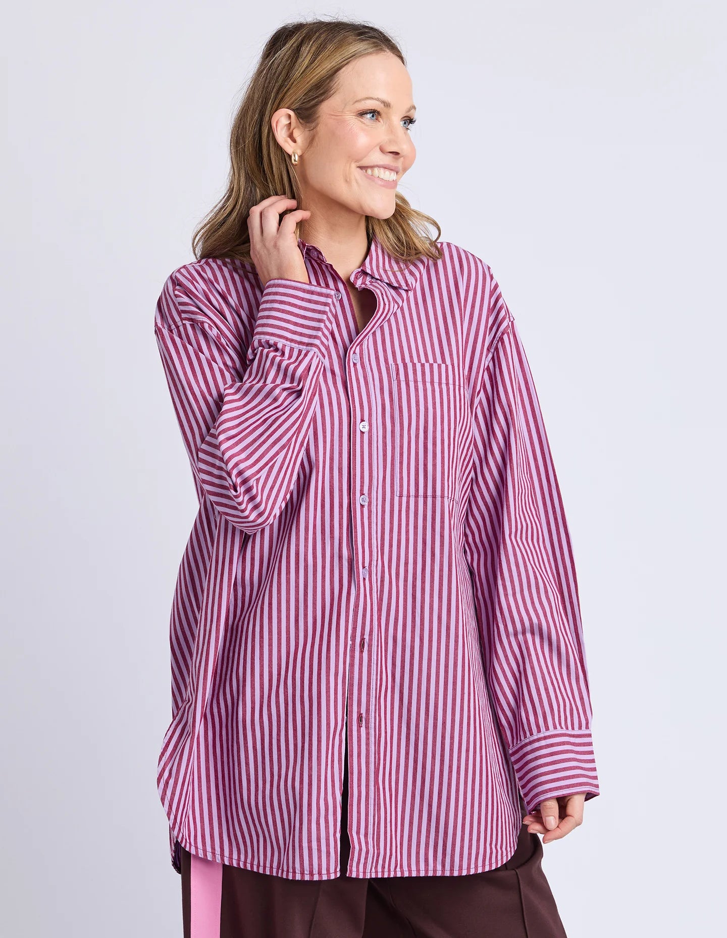 Image of Woman wearing a Elm pink and white striped shirt against a light purple background