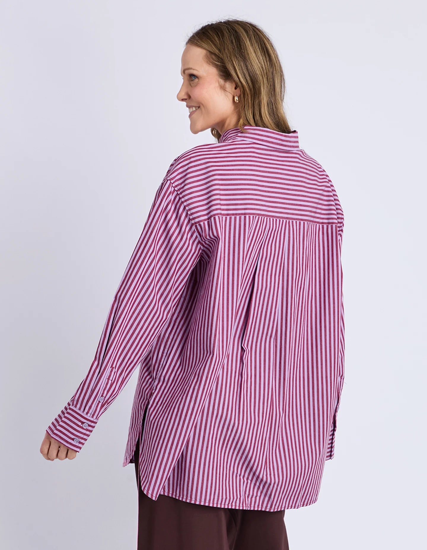 Image of Woman wearing a Elm pink and white striped shirt on a light gray background