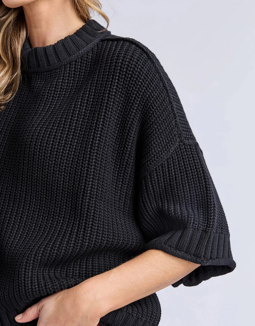 Elm black knit sweater worn by a woman on a light gray background
