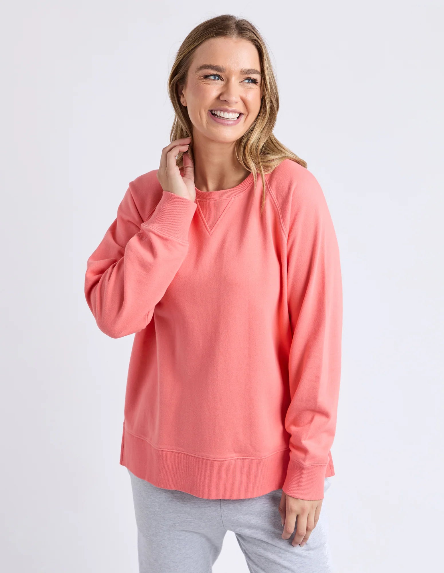 Image of Woman wearing a Elm coral sweatshirt on a white background