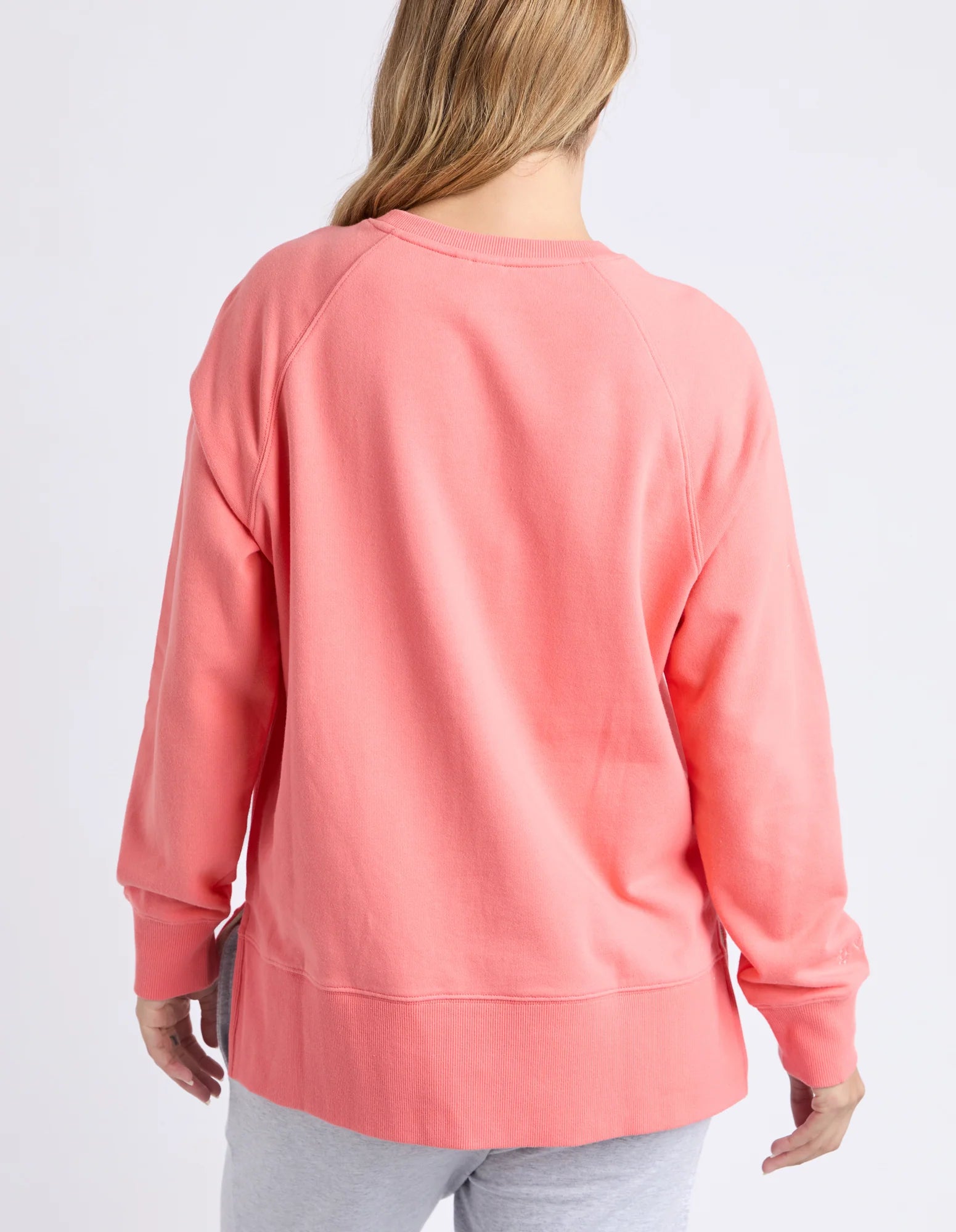 Image of Elm coral sweatshirt worn by a woman on a white background