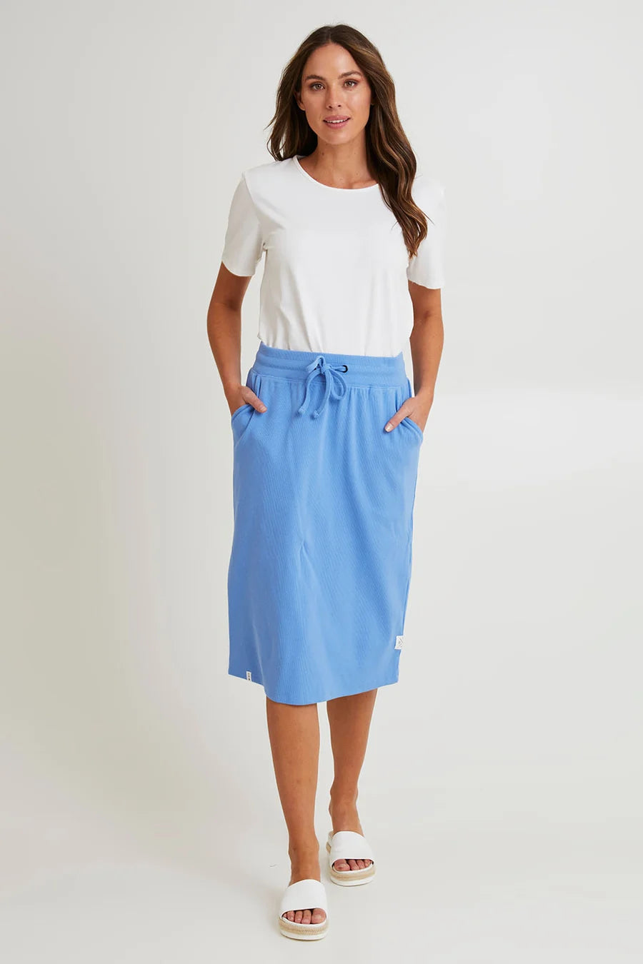 Image of Woman wearing a white top and Elm blue skirt on a plain background