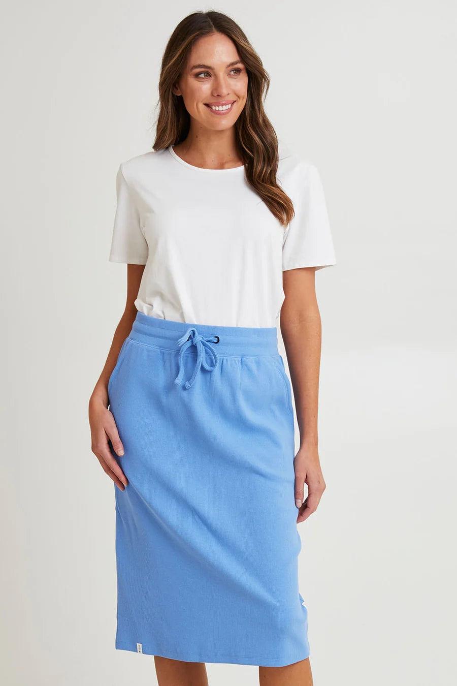 Image of Woman wearing a white top and Elm blue skirt on a plain background