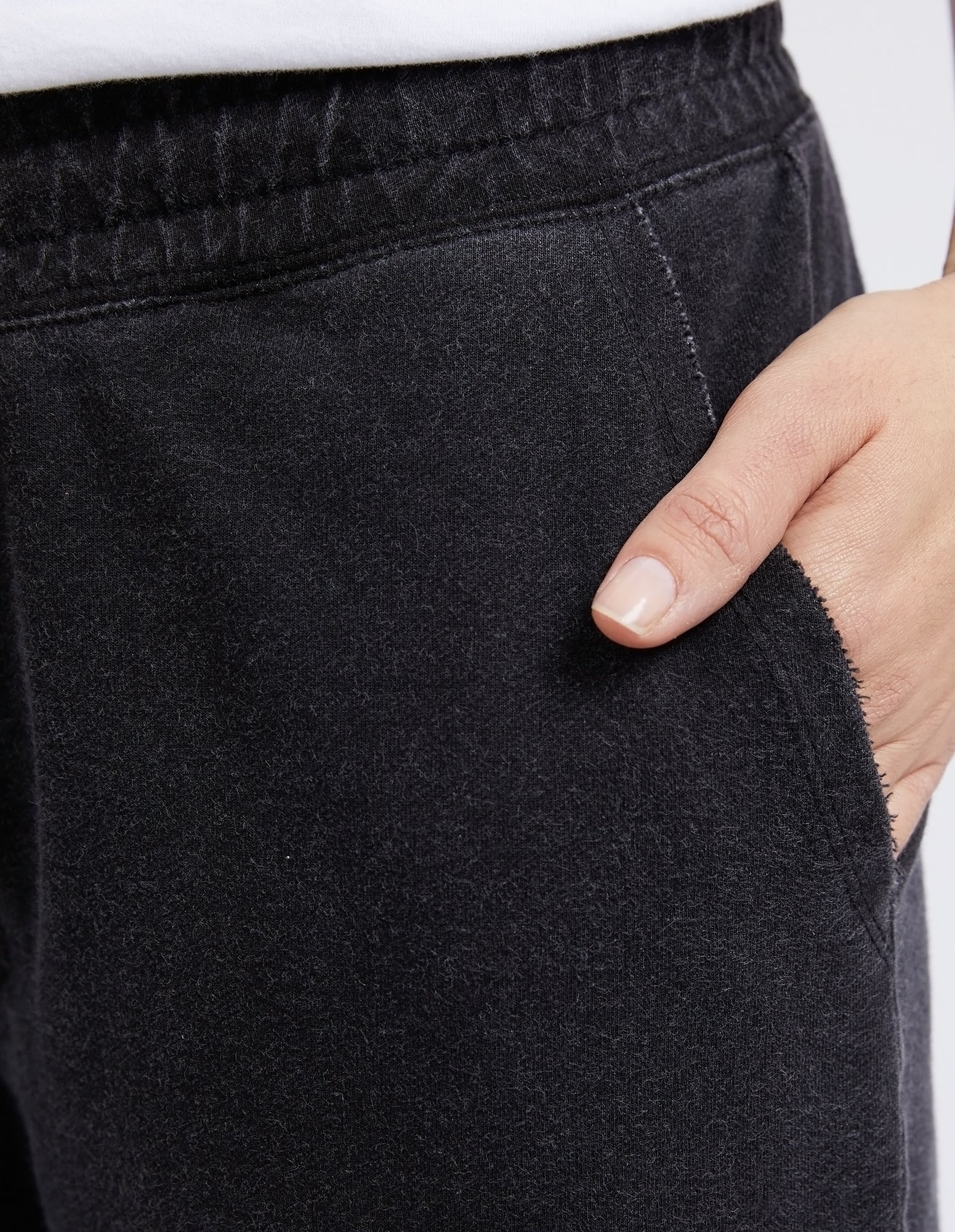 Close-up of a person wearing Elm black pants with a hand in the pocket.