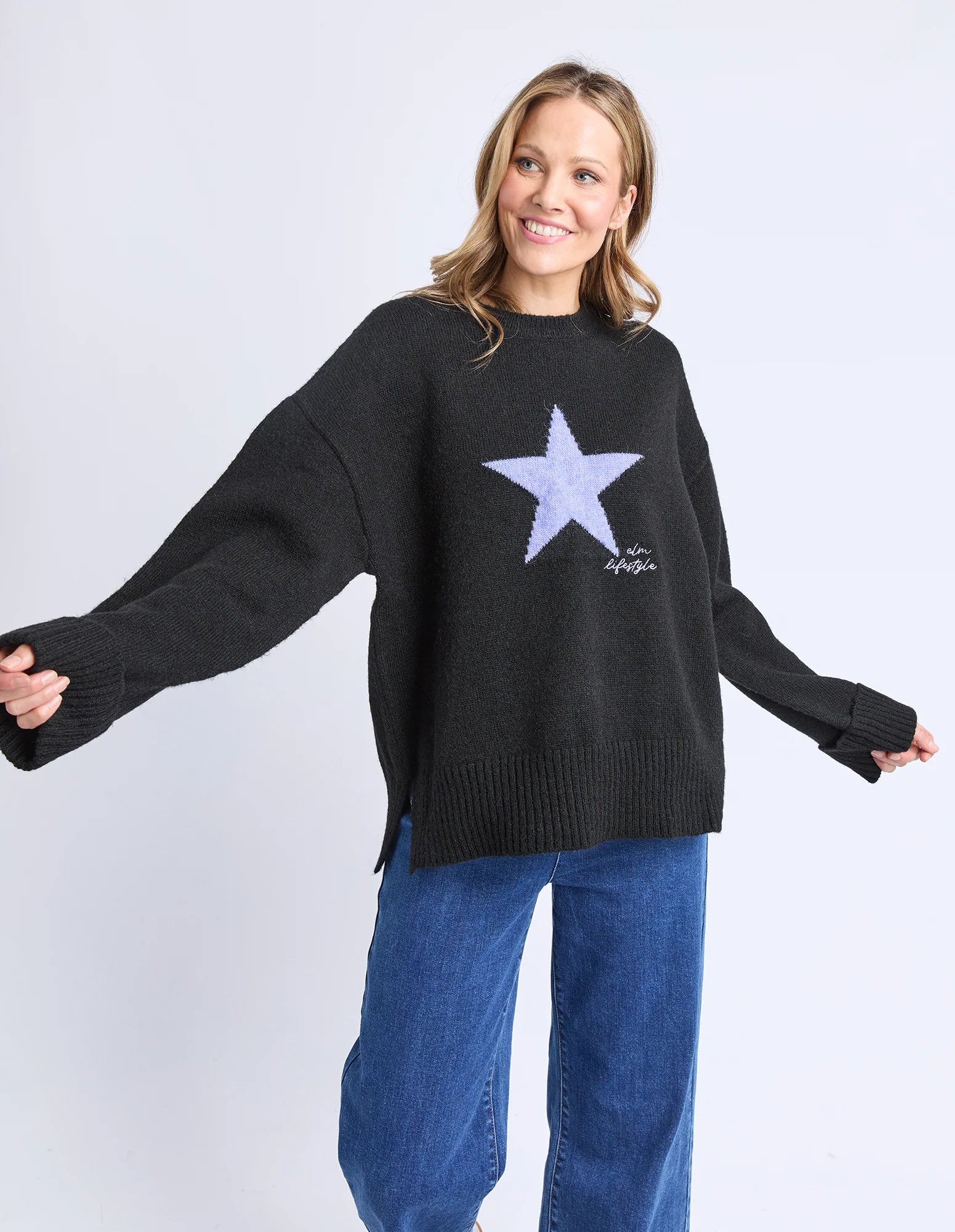 Image of Woman wearing a Elm black sweater with a star design on a white background