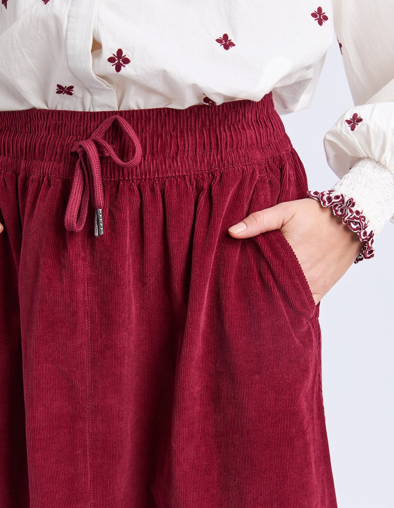 Elm red skirt worn with a white blouse featuring red floral patterns on a white background