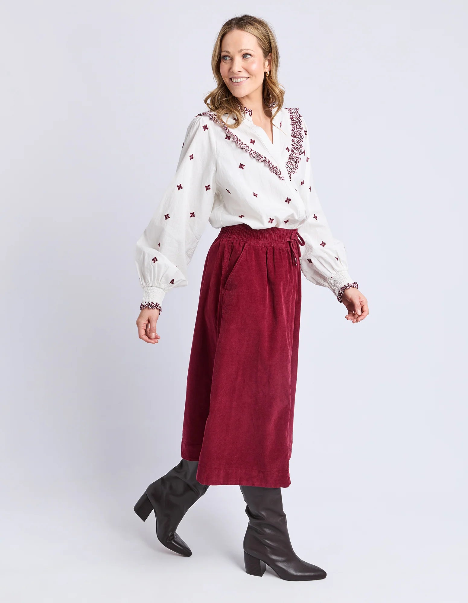Image of Woman wearing a white blouse with red embroidery and a Elm red skirt on a white background