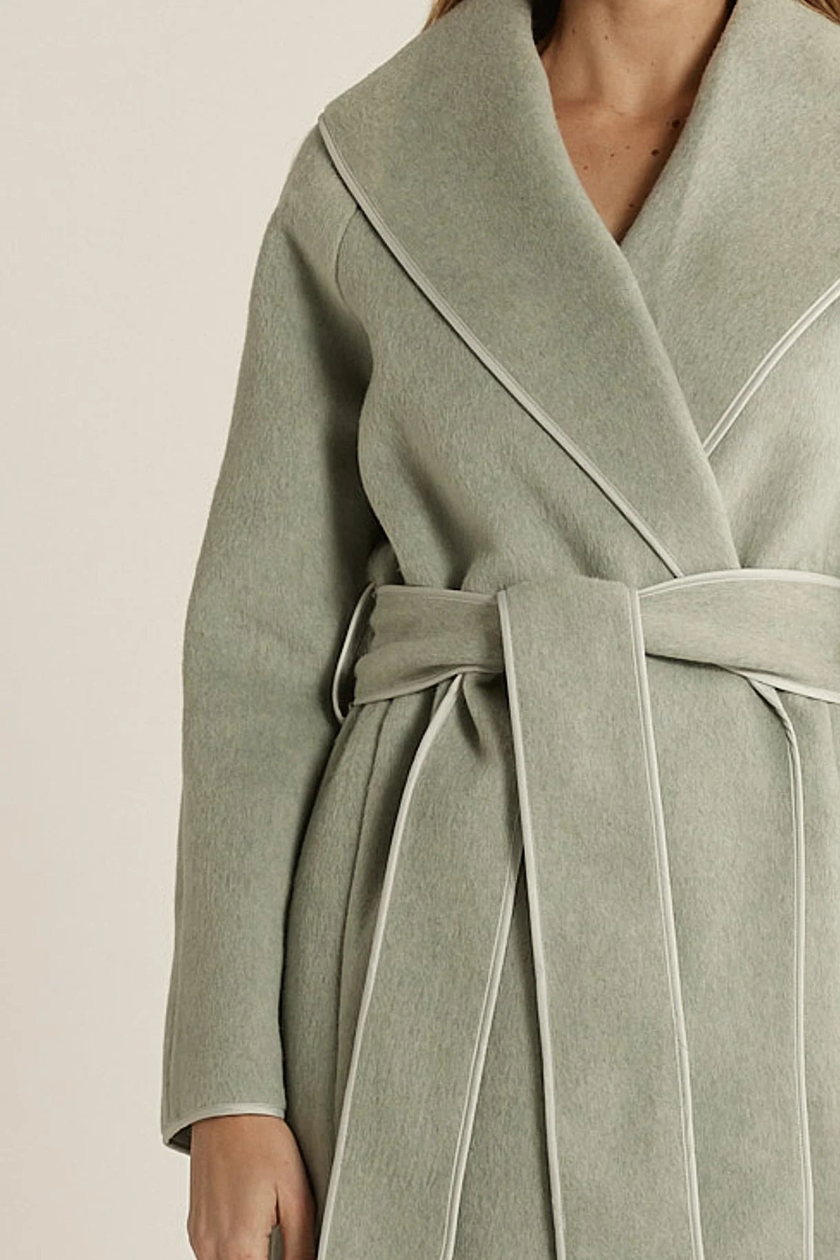 Fate & Becker green coat with a belt on a neutral background