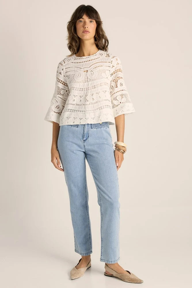 Image of Woman wearing a Fate & Becker white lace top and light blue jeans on a plain background