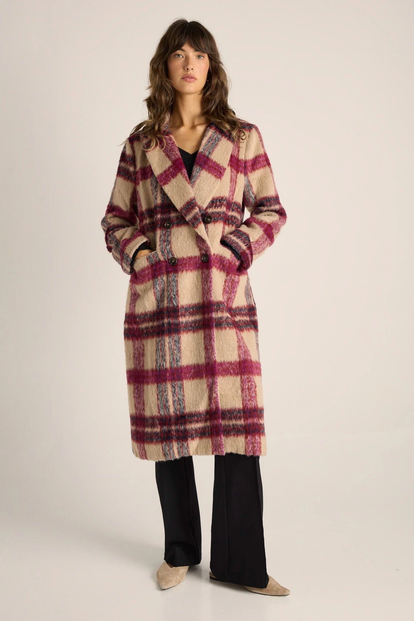 Woman wearing a Fate and Becker plaid coat on a plain background