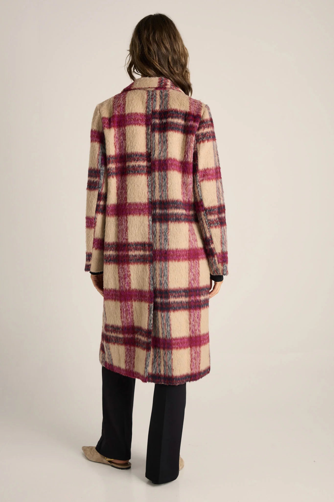 Woman wearing a Fate and Becker plaid coat on a plain background