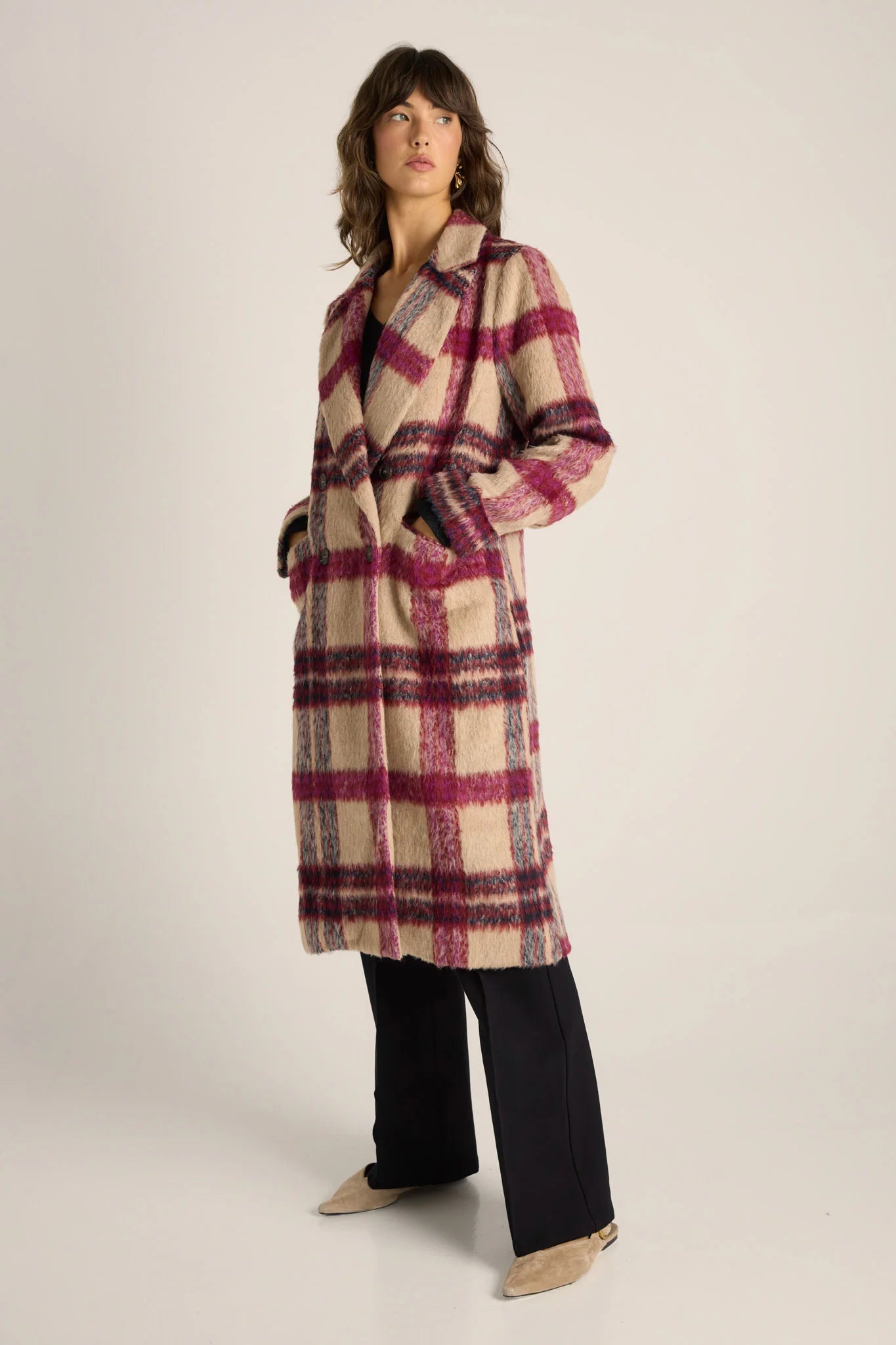 Woman wearing a Fate and Becker plaid coat on a plain background