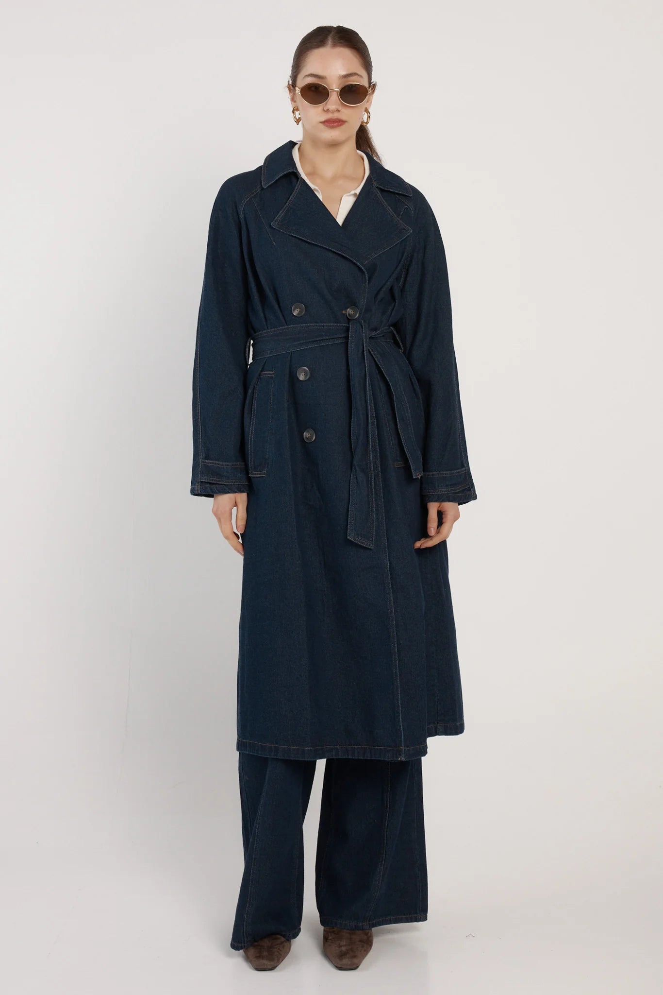 Image of Woman wearing a Fate & Becker navy trench coat on a white background
