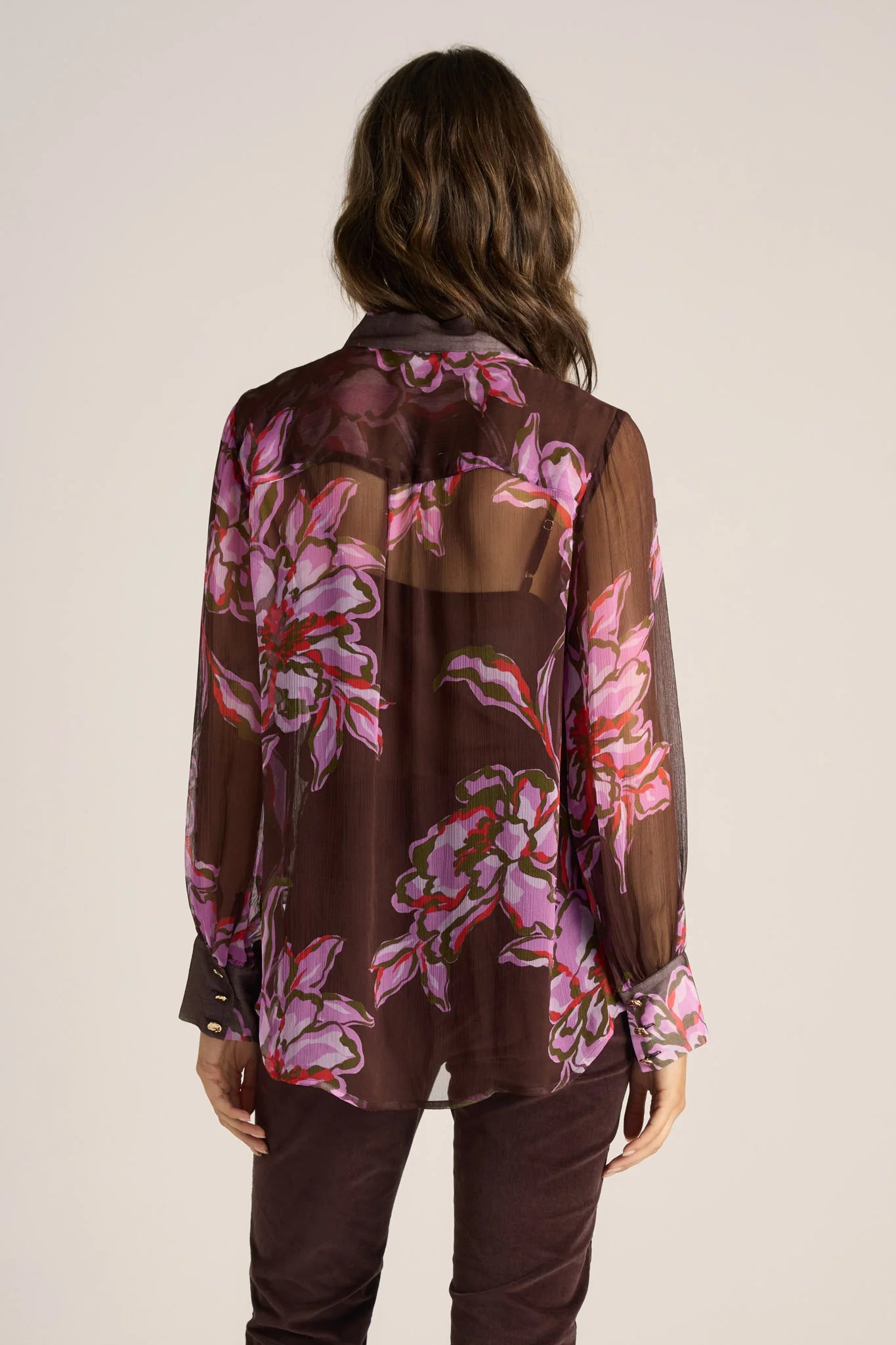 Woman wearing a Fate and Becker sheer floral blouse with a plain background