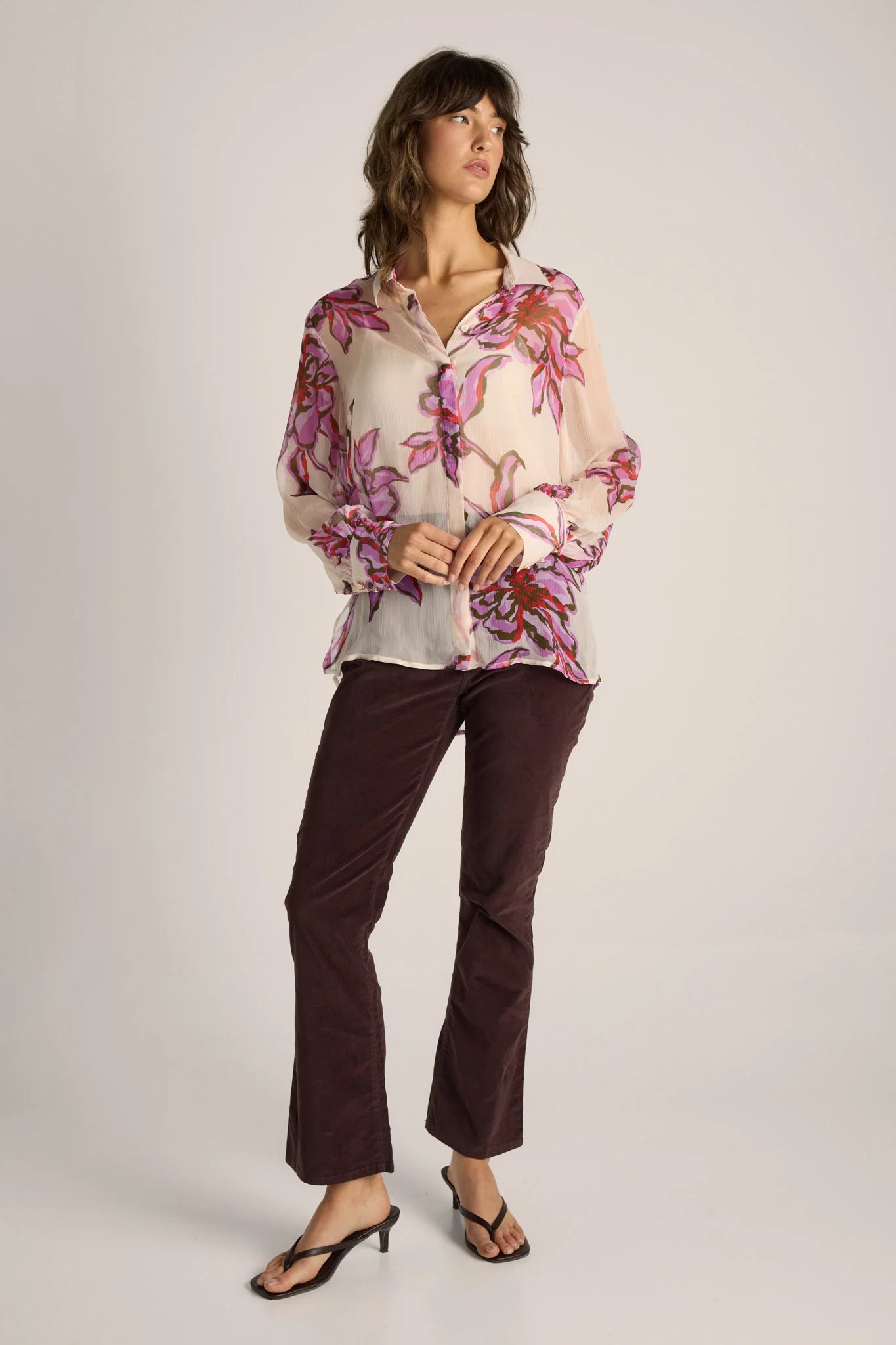 Image of Woman wearing a Fate & Becker floral blouse and brown pants on a white background