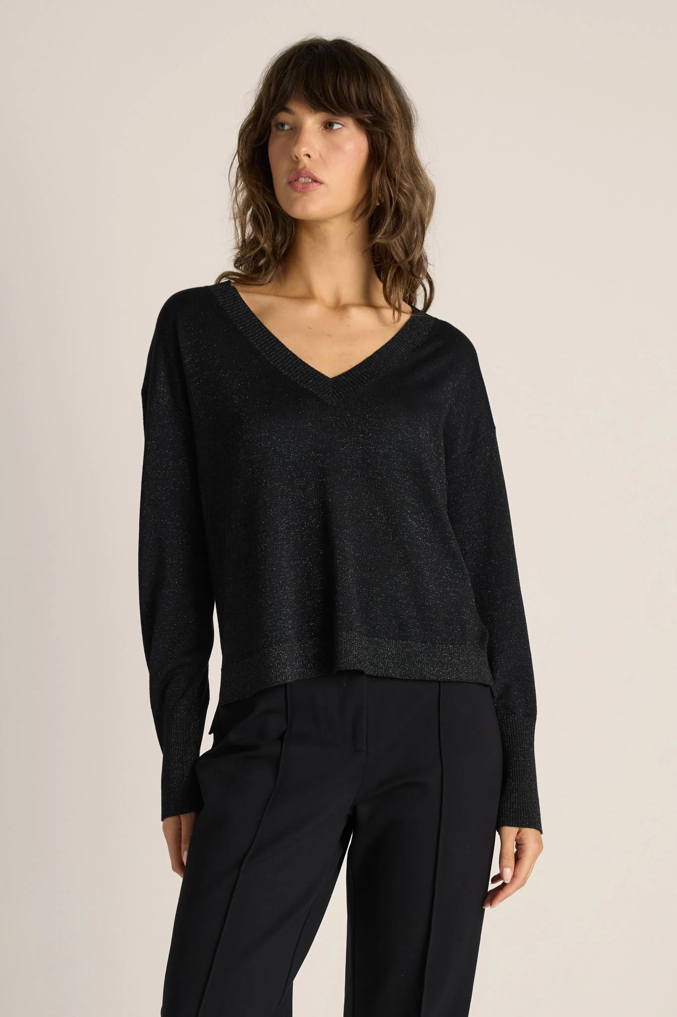 Image of Woman wearing a Fate & Becker black sweater and pants on a beige background