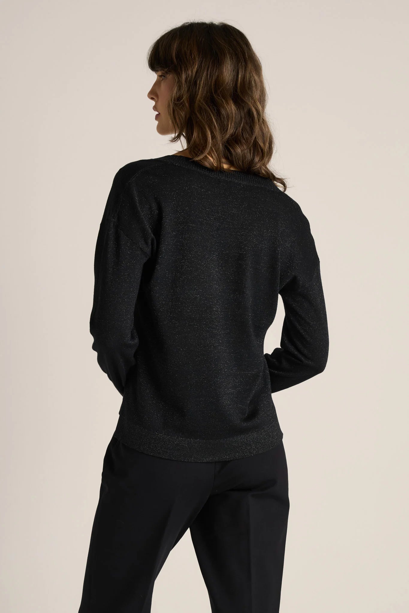 Person wearing a Fate & Becker black sweater and pants on a beige background