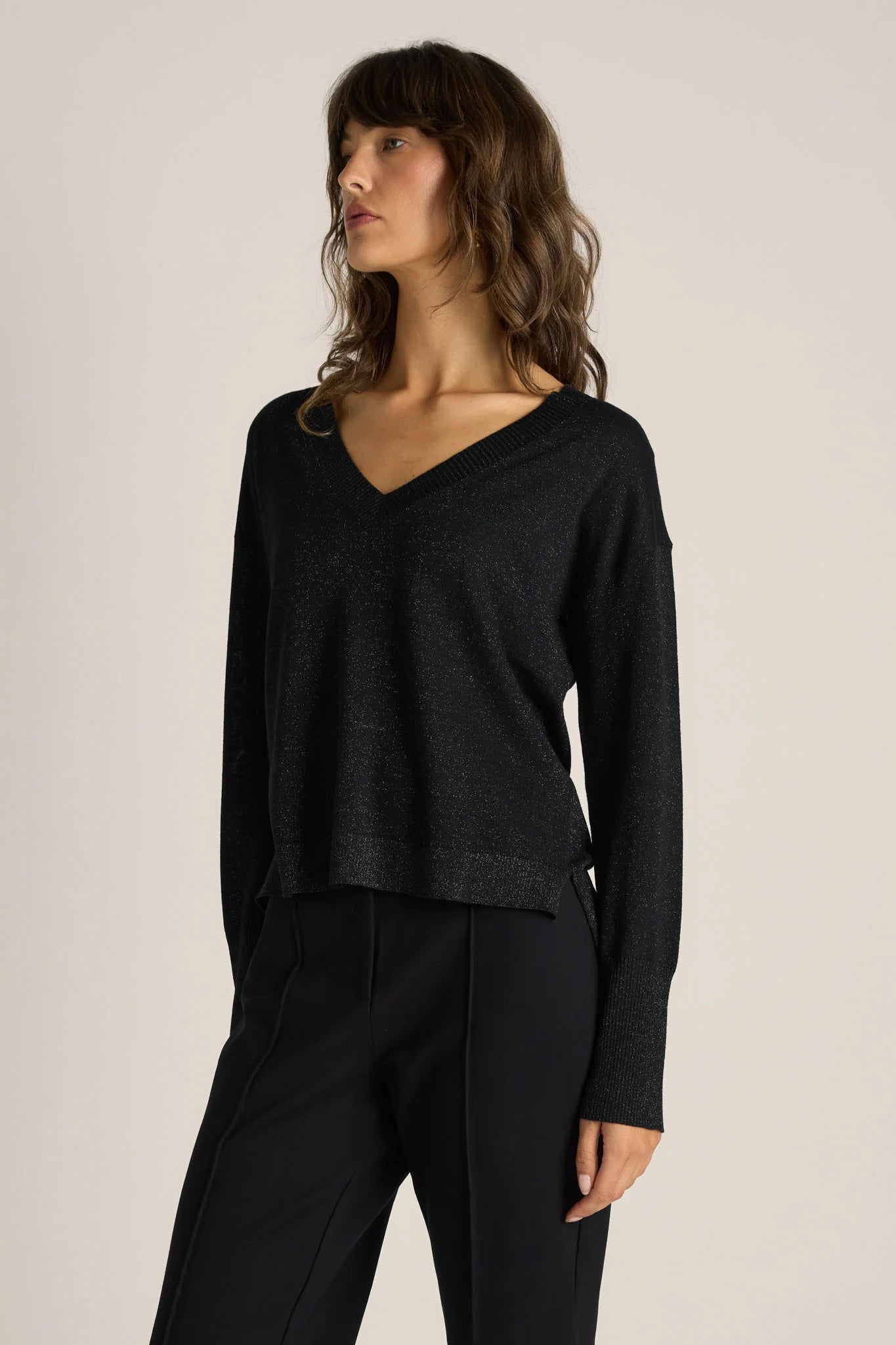 Woman wearing a Fate & Becker black long-sleeve knit and black pants against a plain background