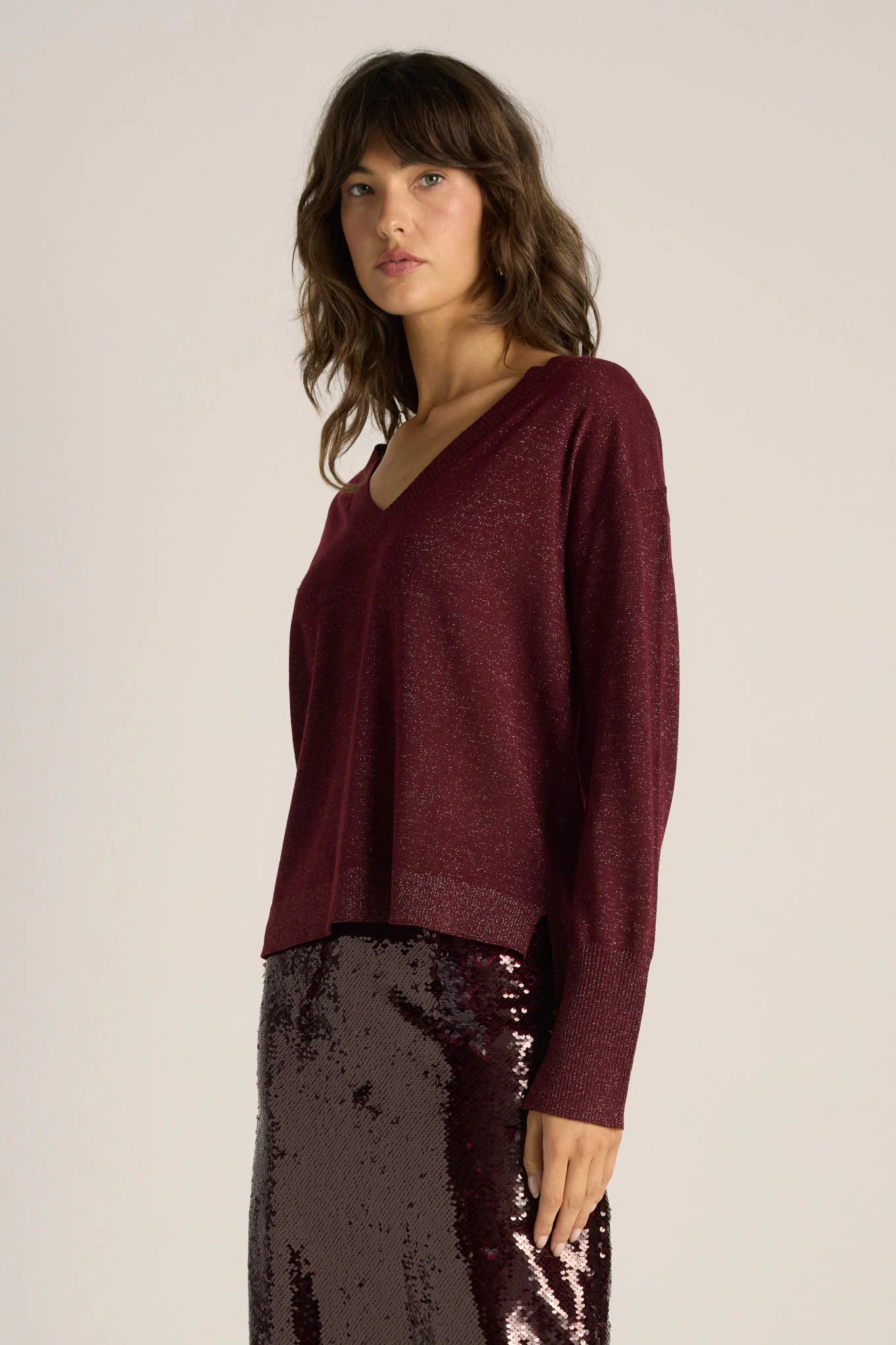 Image of Woman wearing a Fate and Becker burgundy sweater and dark sequin skirt on a plain background