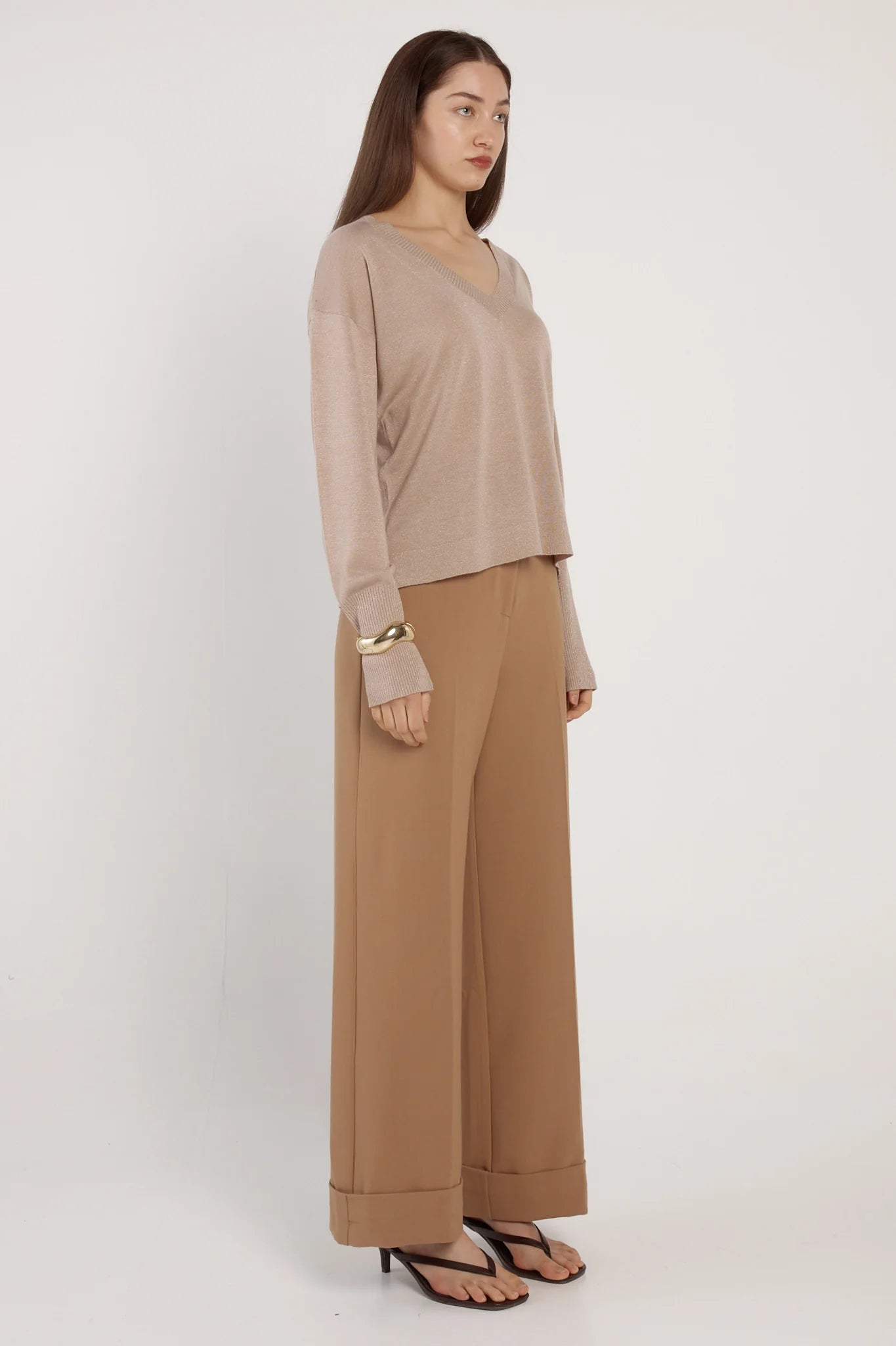Woman wearing a Fate & Becker beige top and brown pants against a white background