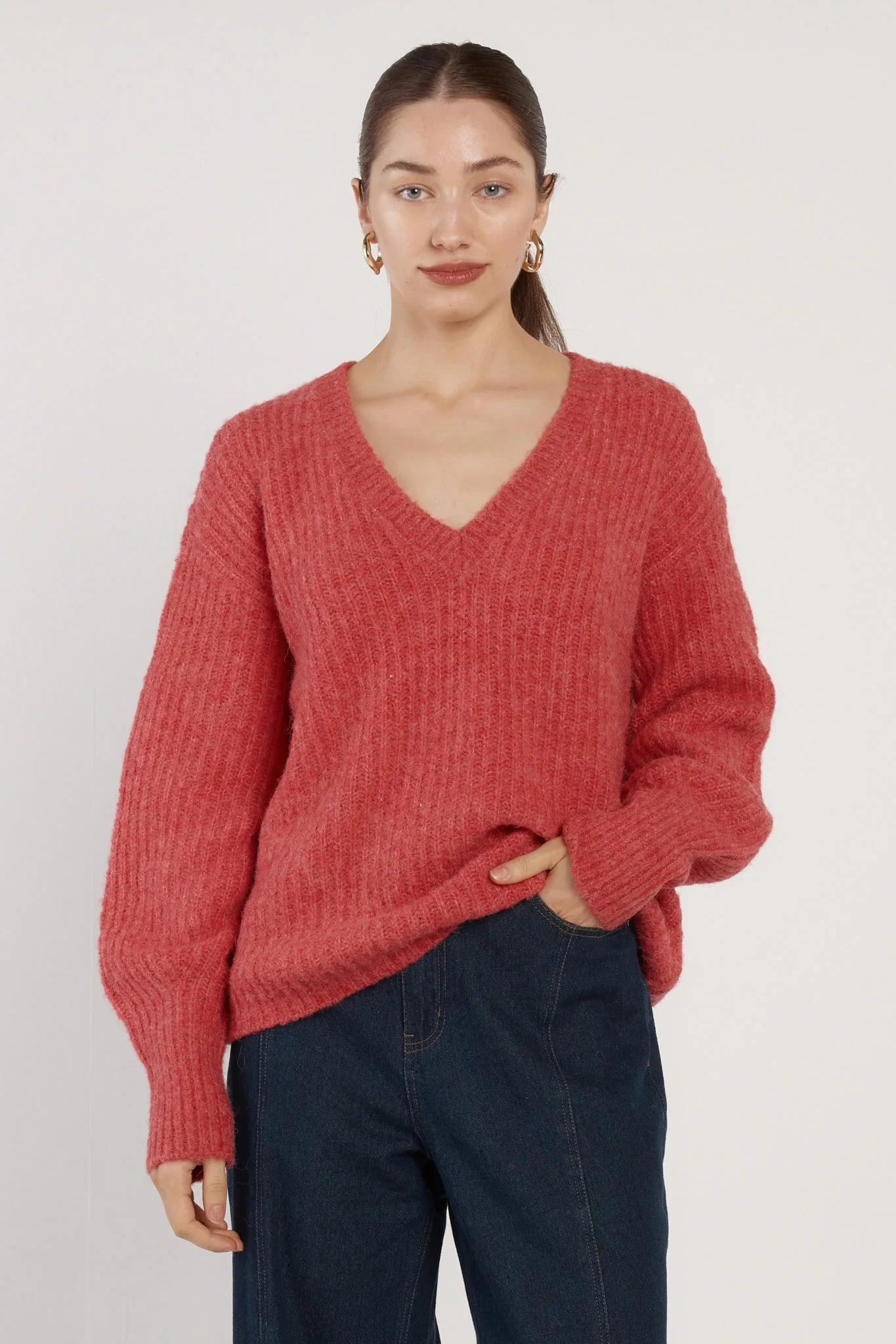 Woman wearing a Fate and Becker red sweater against a white background