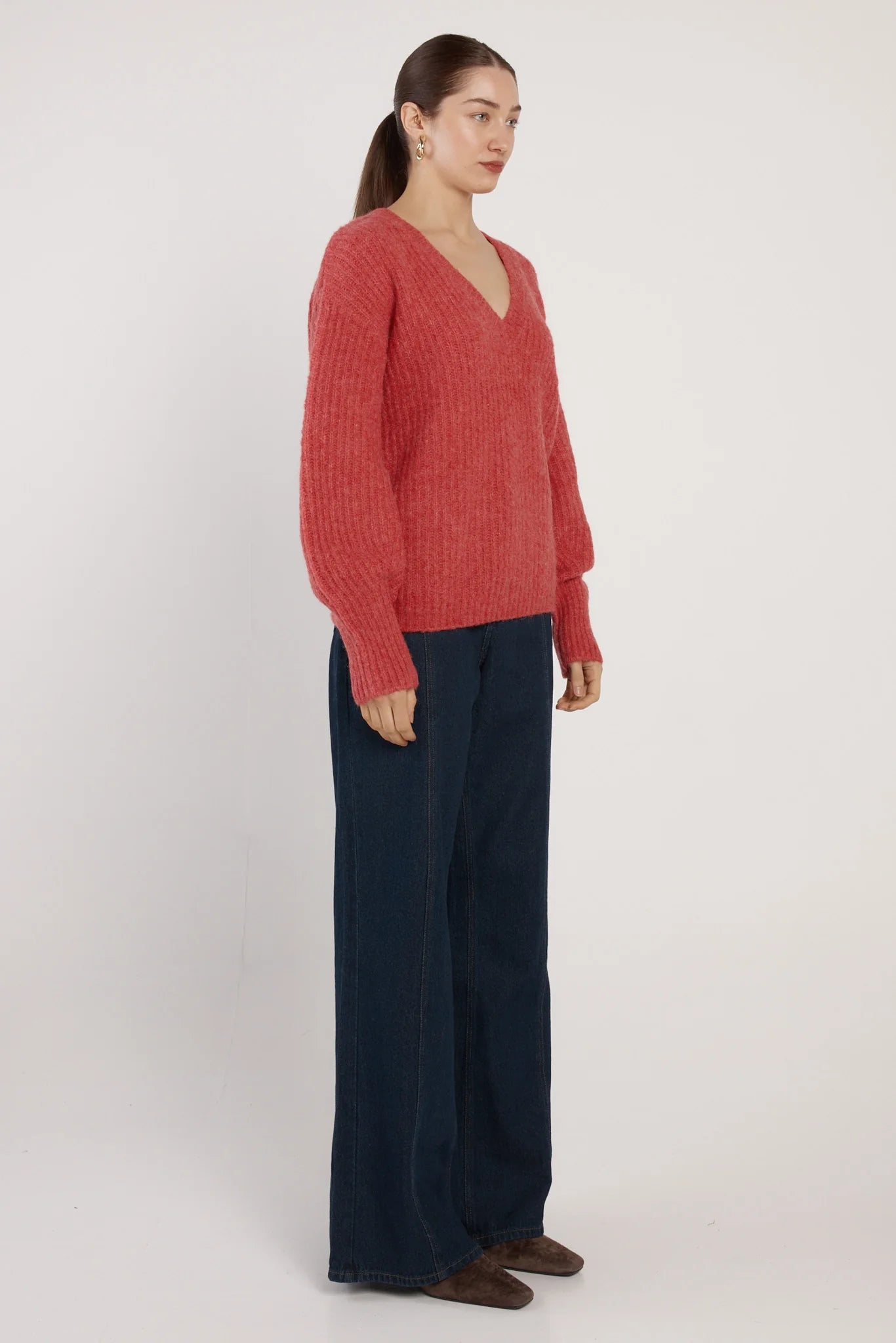 Image of Woman wearing a Fate and Becker red sweater and dark pants on a white background