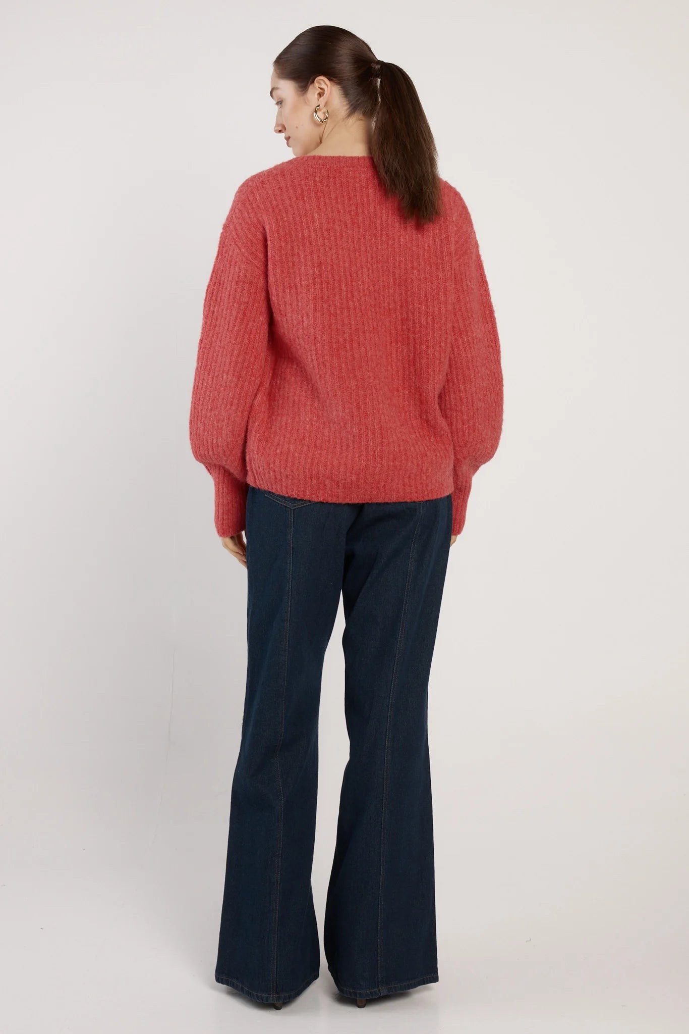 Image of Woman wearing a Fate and Becker red sweater and dark blue pants on a white background