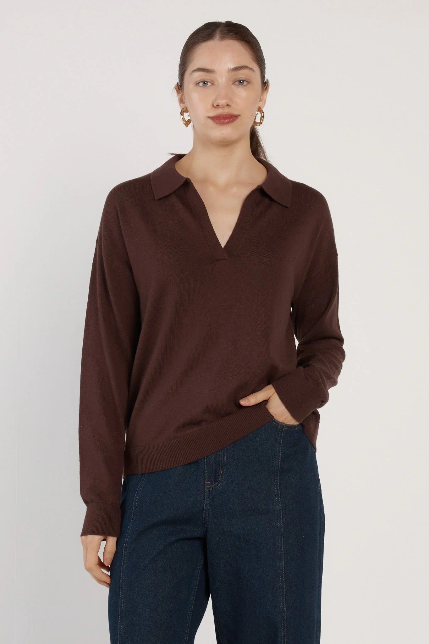 Woman wearing a Fate and Becker brown long-sleeve shirt and dark blue pants on a white background