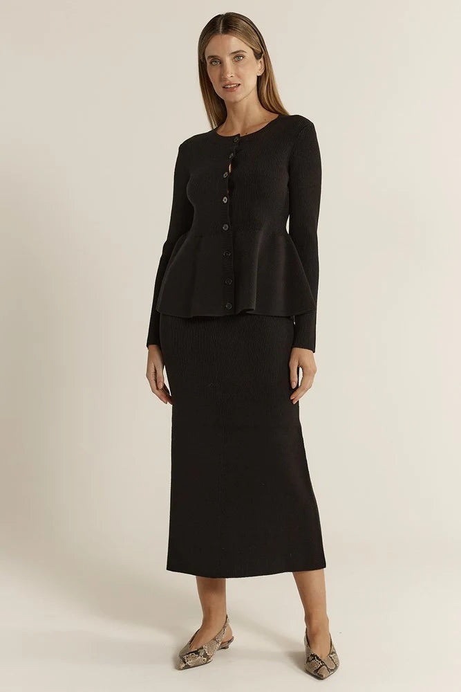 Woman wearing a Fate & Becker black outfit with a long-sleeve top and skirt on a plain background