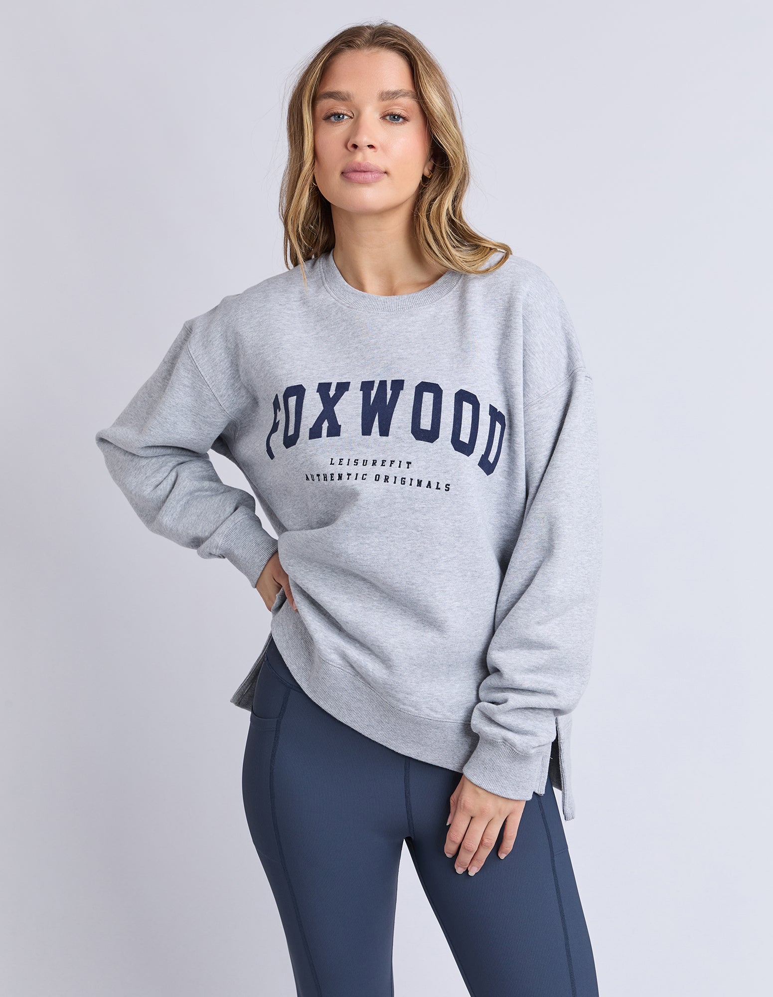 Image of Woman wearing a grey jumper with 'Poxwood' branding on a light grey background