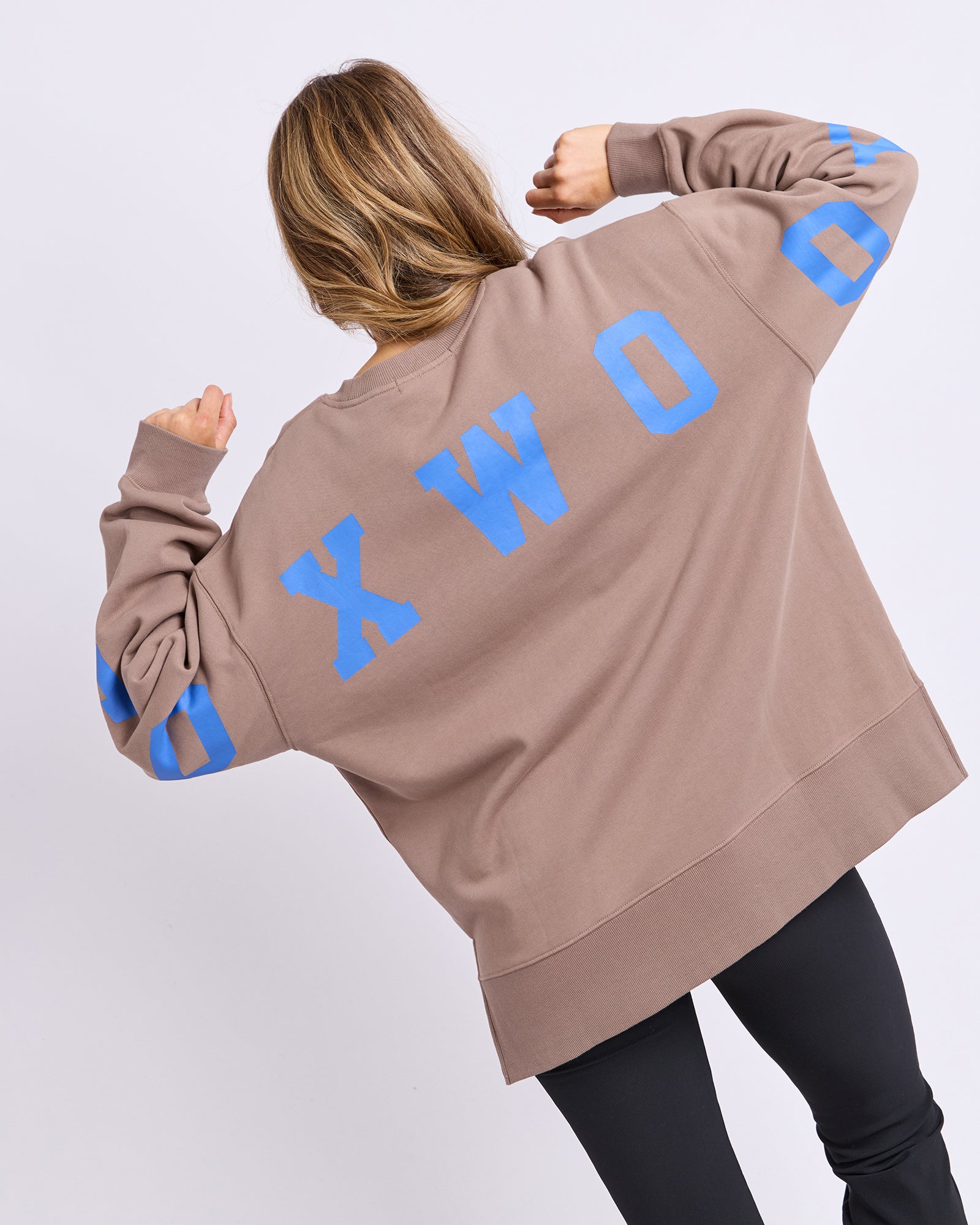 Back view of a woman wearing a Foxwood Brown jumper with blue text on a white background