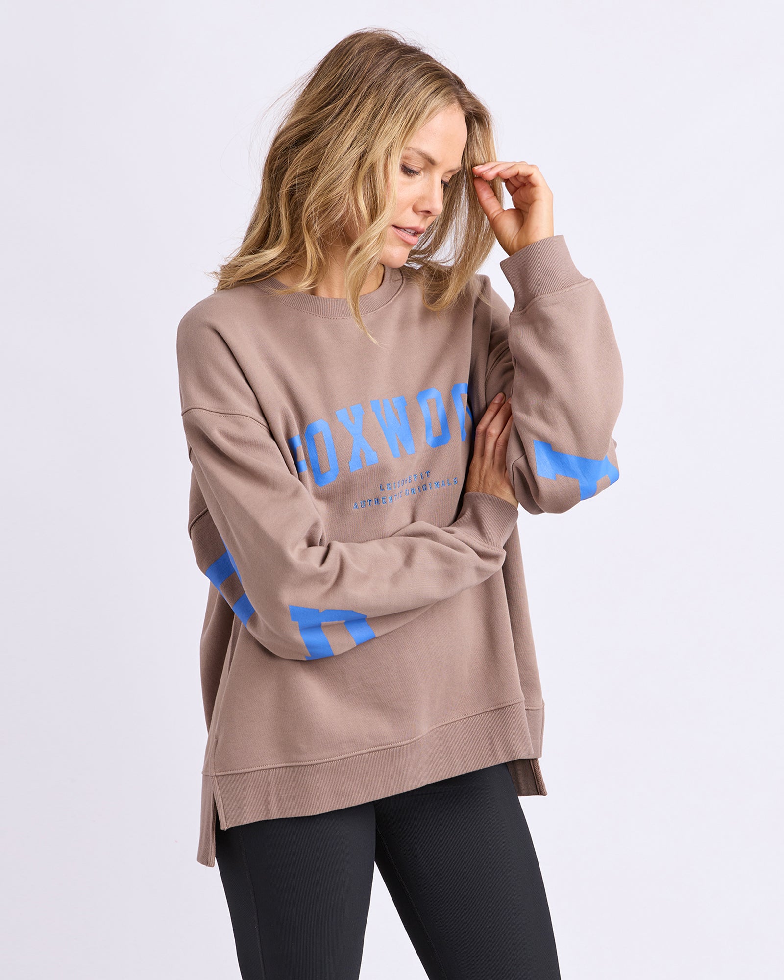 Collection of Woman wearing a Foxwood Interval crew brown jumper with blue text on a light grey background in a gallery layout