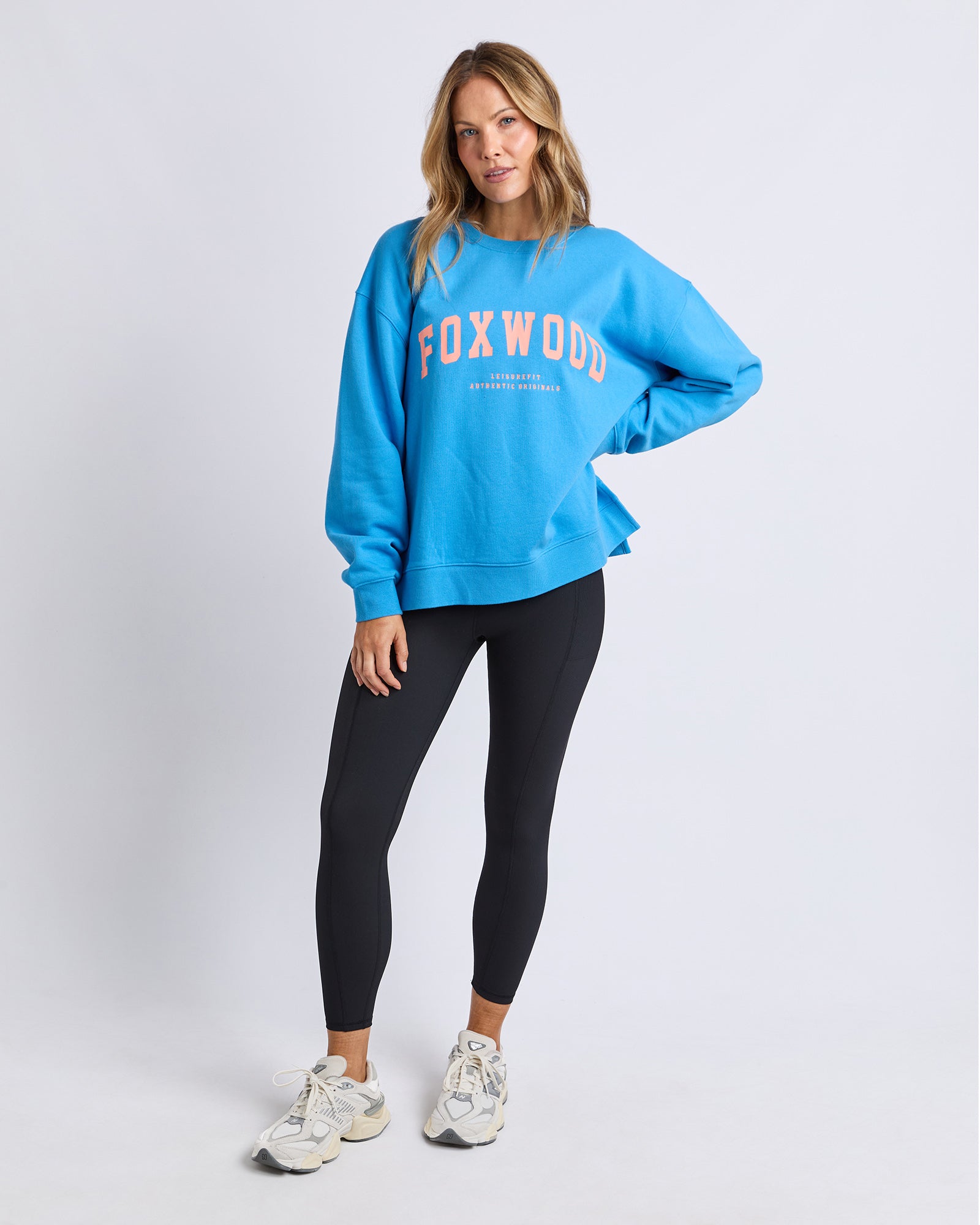 Woman wearing a Foxwood bright blue jumper with 'FOXWOOD' printed on it in orange against a white background
