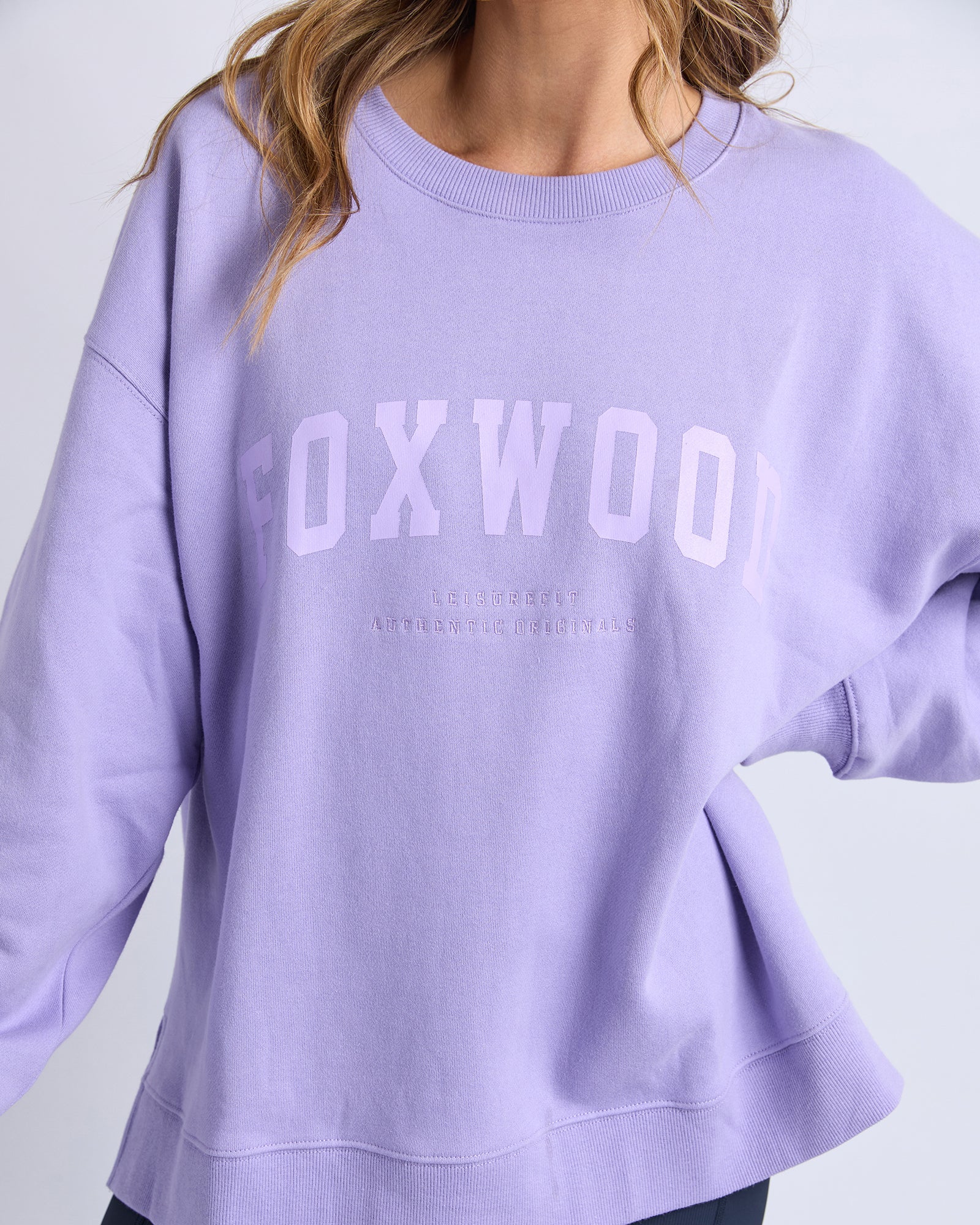 Collection of Lavender sweatshirt with 'FOXWOOD' printed on it against a light gray background in a gallery layout