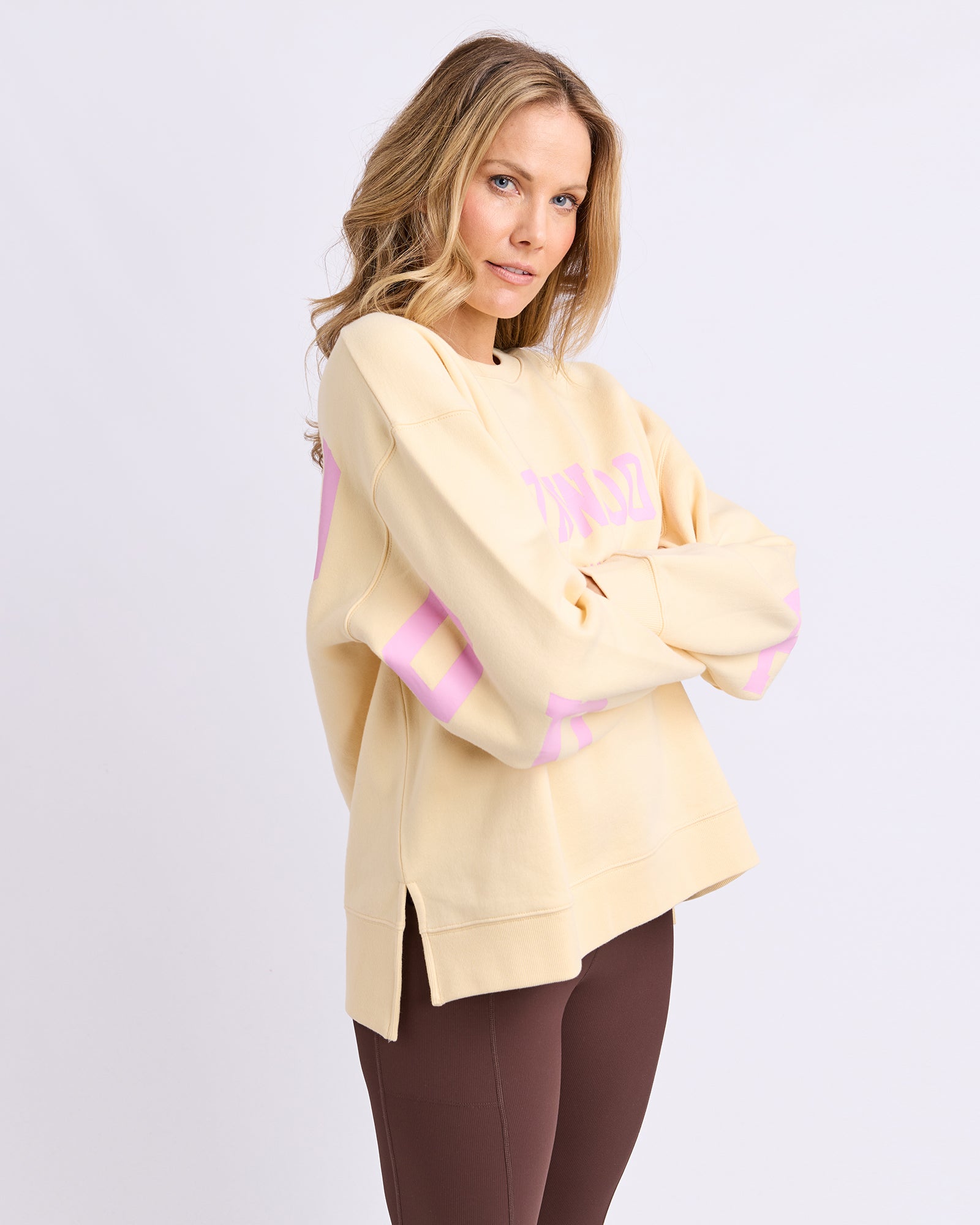 Woman wearing a Foxwood light yellow jumper with pink print on a white background