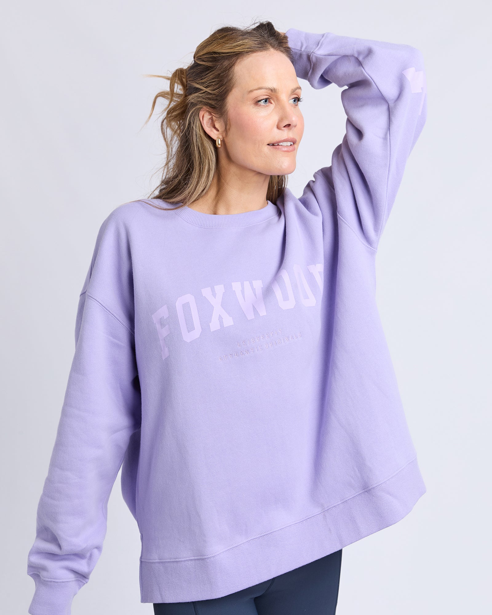 Woman wearing a light purple /lavender jumper with 'FOXWOOD' text on a plain background