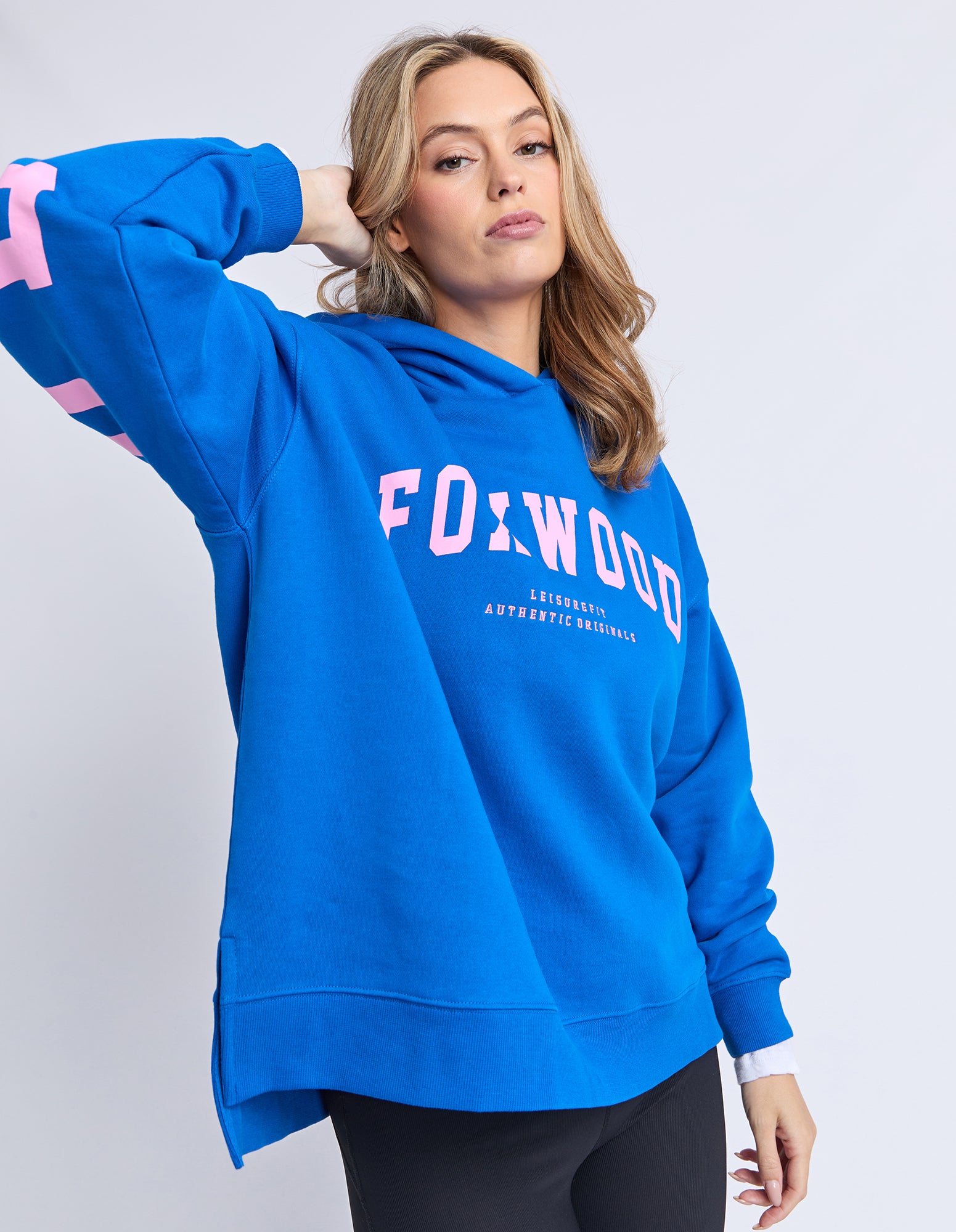 Image of Woman wearing a blue hoodie with 'Foxwood' text in pink on a white background